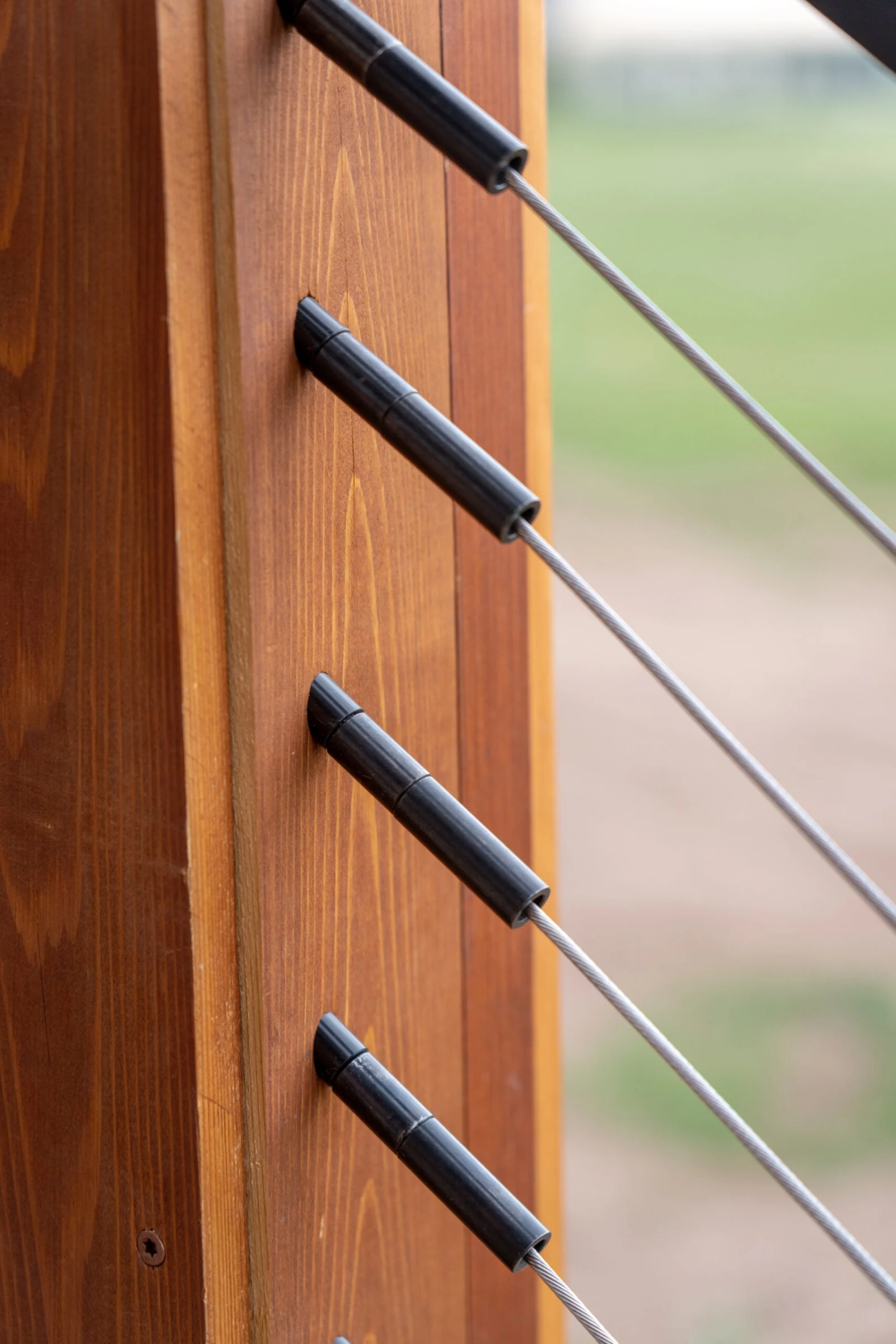 Close view of black cable fittings set into the face of a wood post