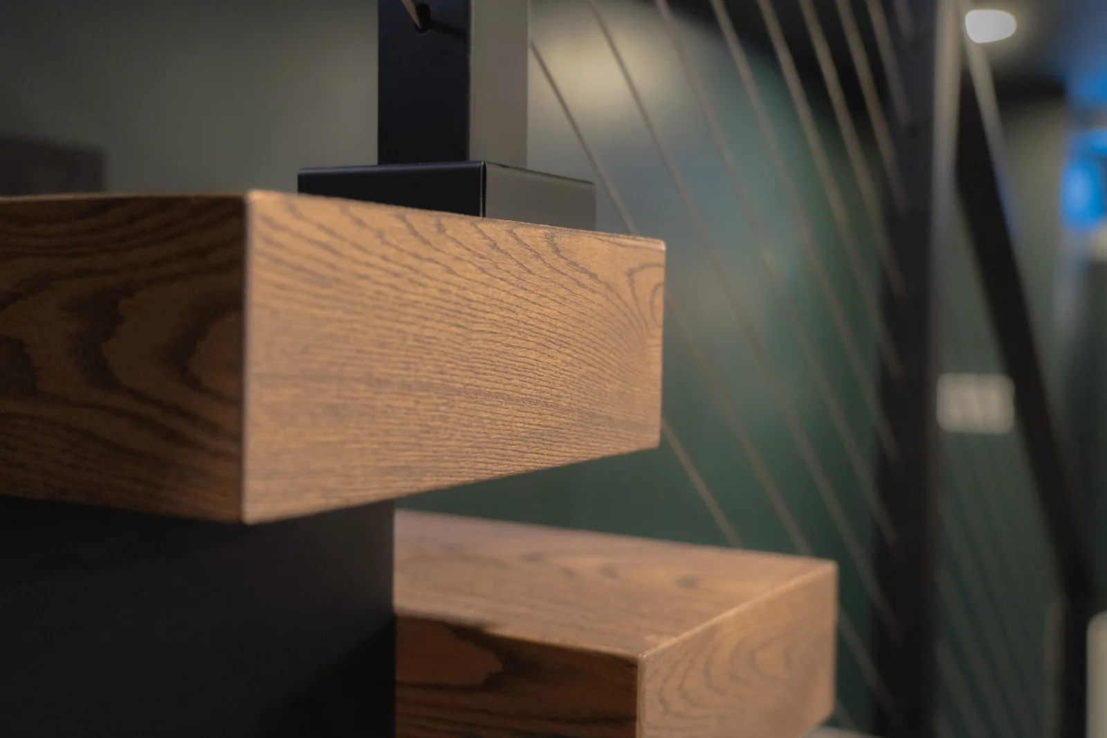 Close view of two thick wood treads meeting a black stringer with cables behind