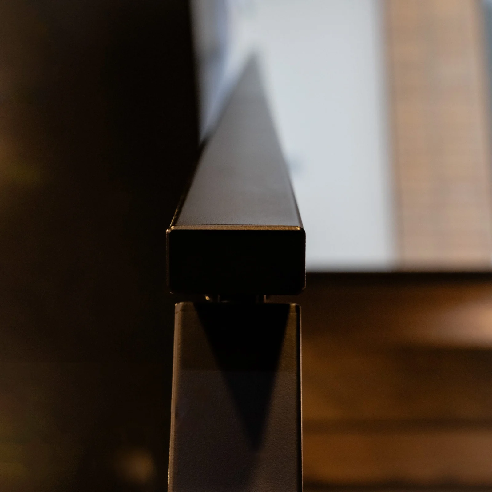 Tight view along the squared black top rail toward the treads beyond
