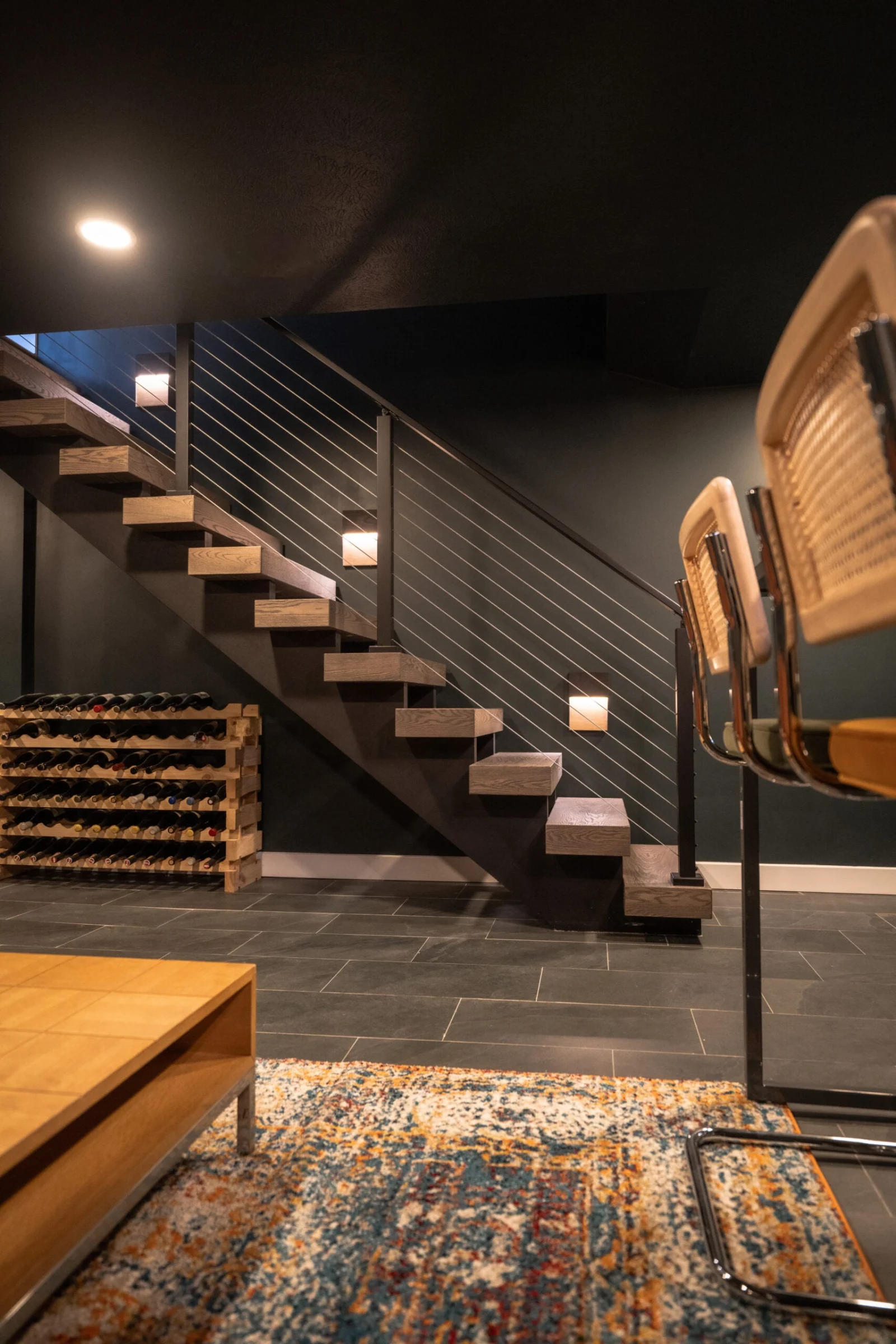Lower level with the stair, wine racks and a patterned rug underfoot