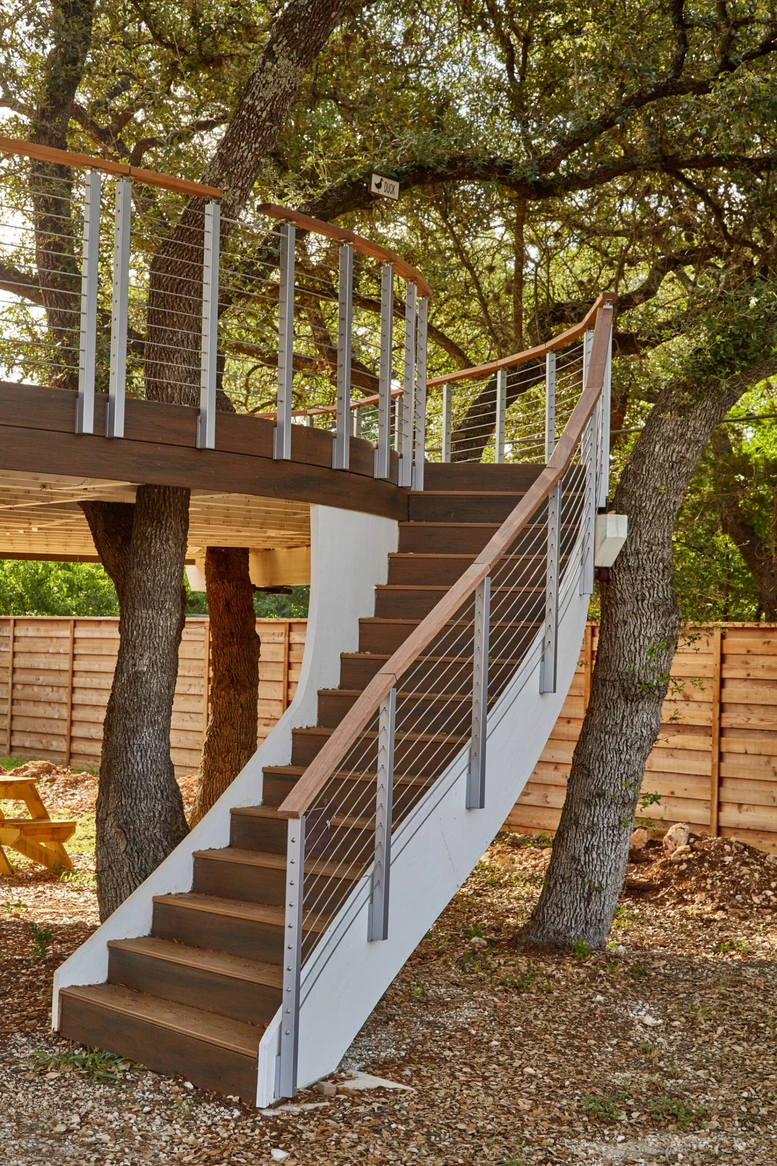 Straight stair climbing to the raised deck platform, railing lining both runs