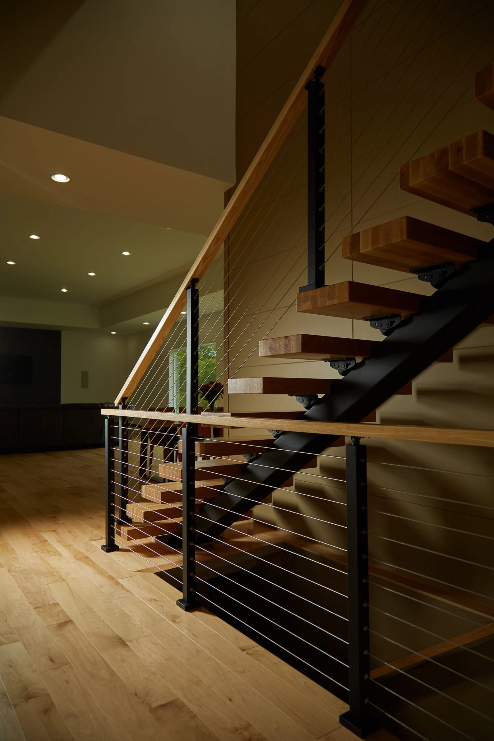 Floating stair seen down a hallway with cable railing guarding the overlook