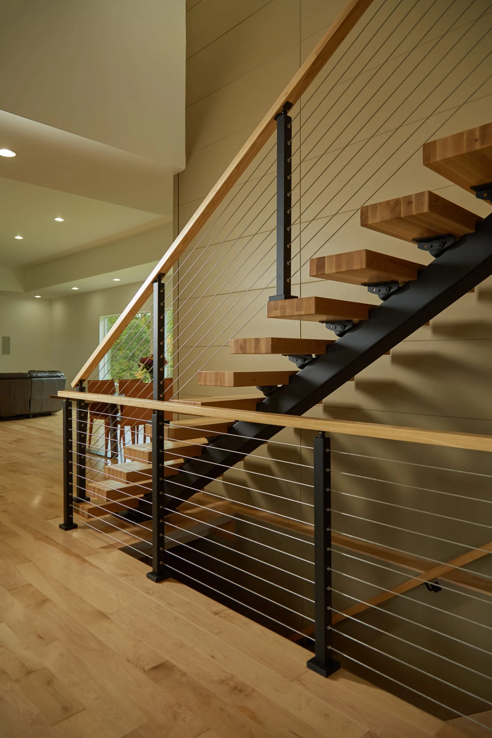 Open treads and balcony cable railing against a paneled two-story wall