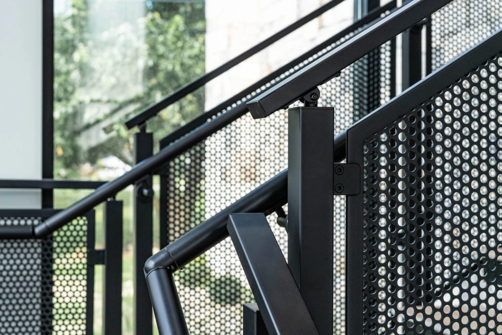 Close view of a black post, top rail and perforated panel infill