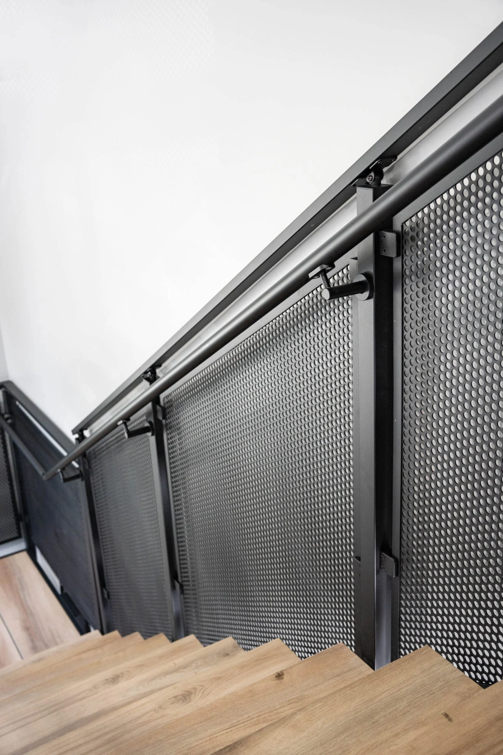 View down the flight along perforated panels and a wall-mounted handrail