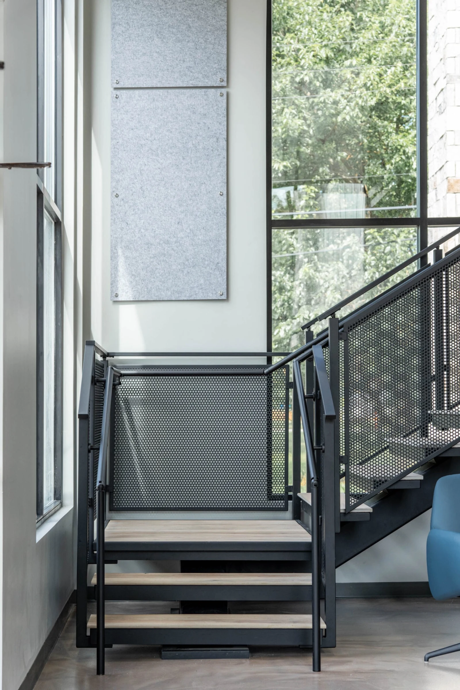 Lower run of porcelain treads climbing to a landing beside a floor-to-ceiling window