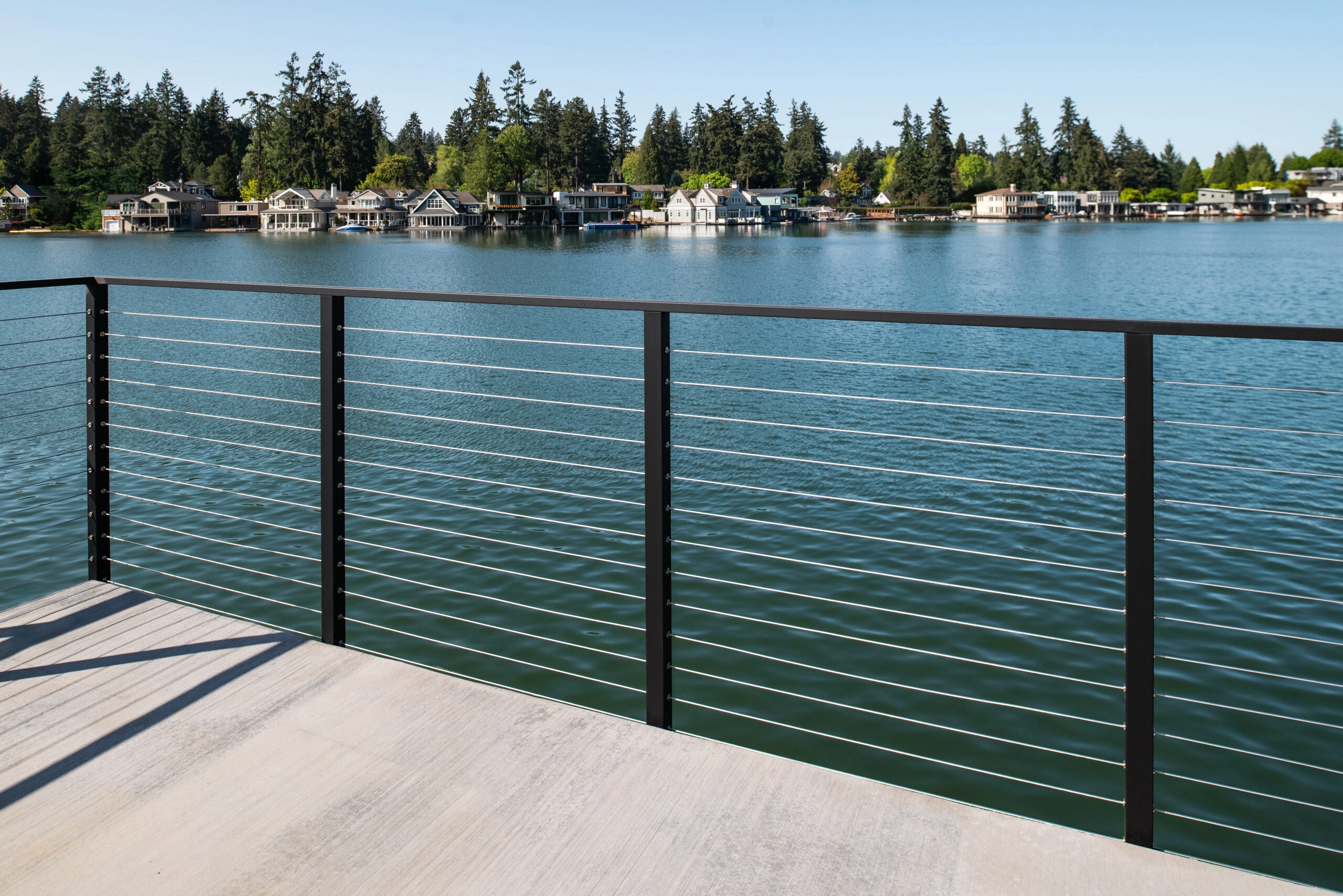 Long cable railing run framing the lake and far shoreline homes