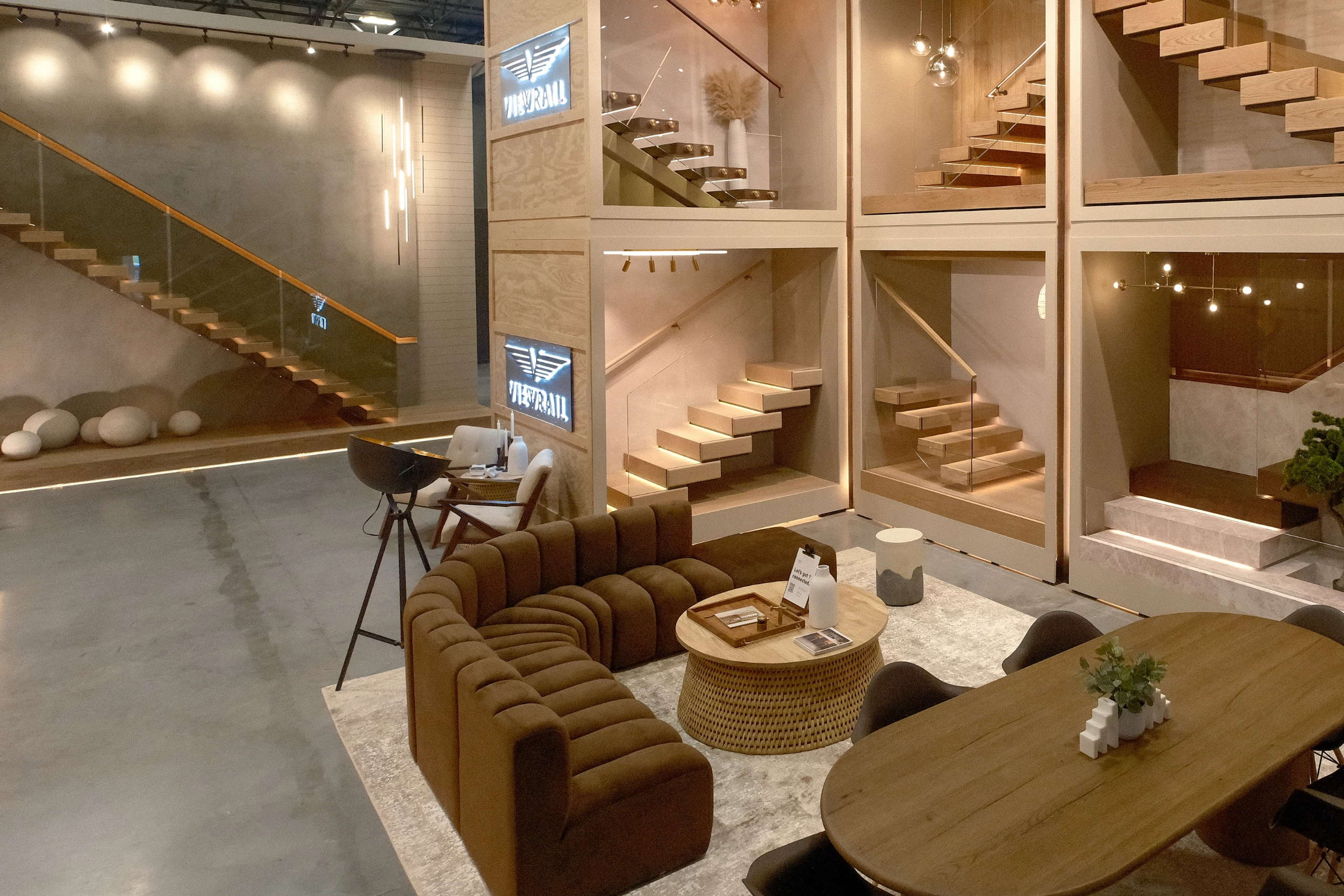 Showroom lounge seating sits beneath stair displays and wall-mounted screens