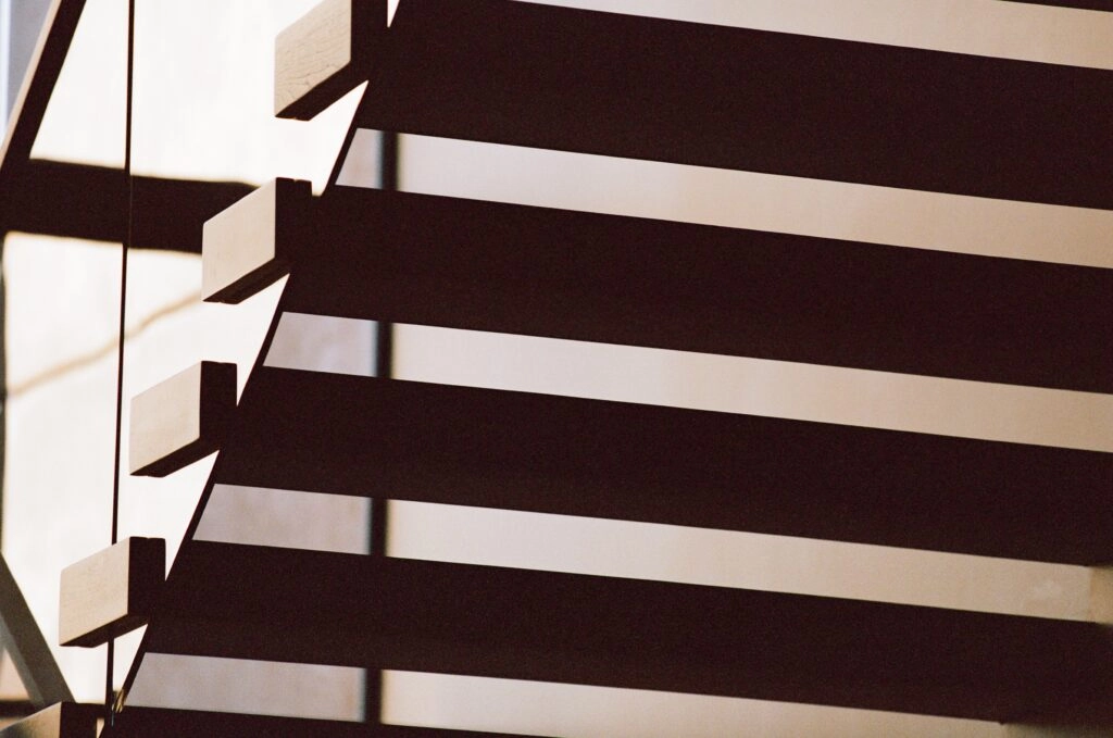 Angled treads and their shadows stripe a sunlit interior wall
