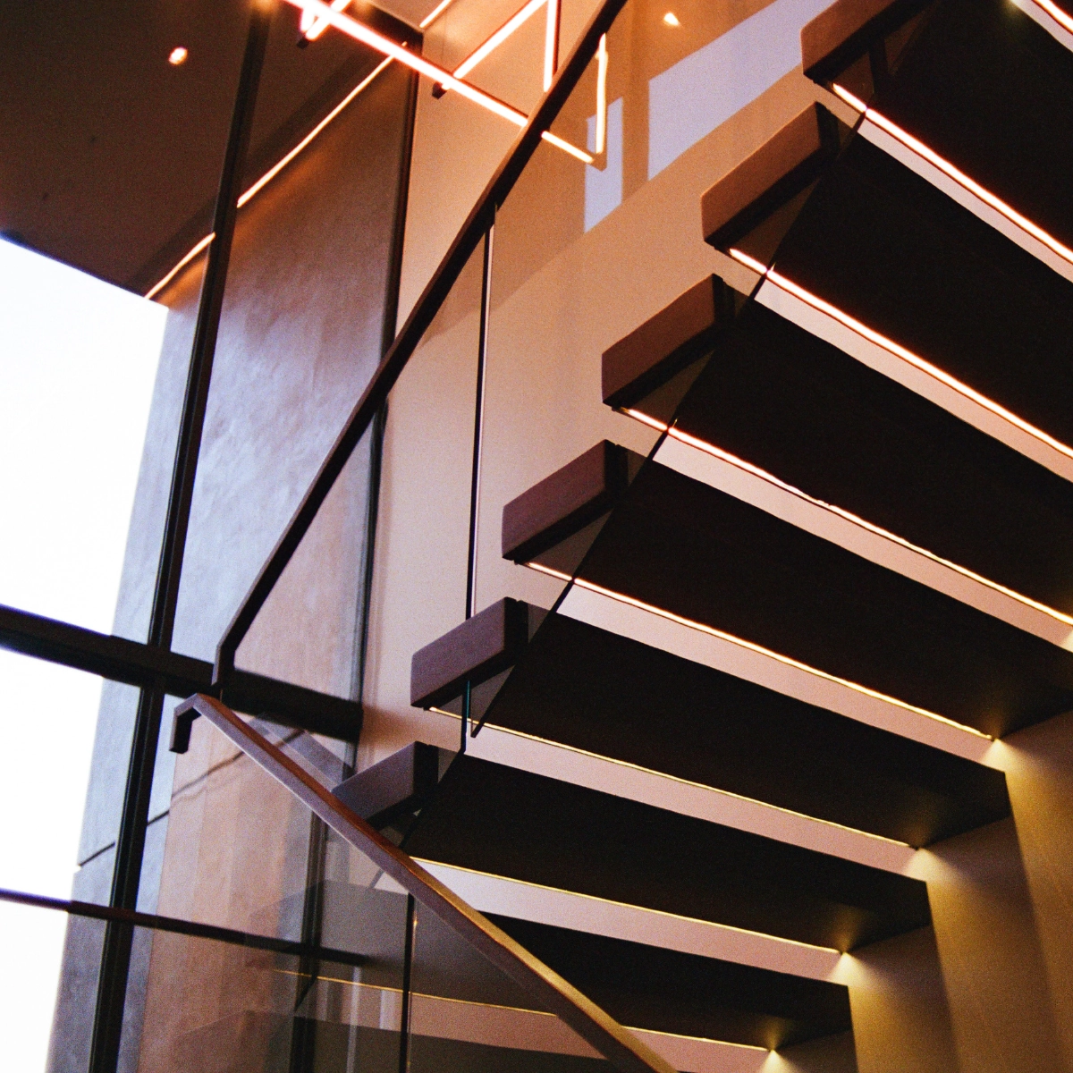Lit cantilevered treads step up a wood-clad wall in a tall entry