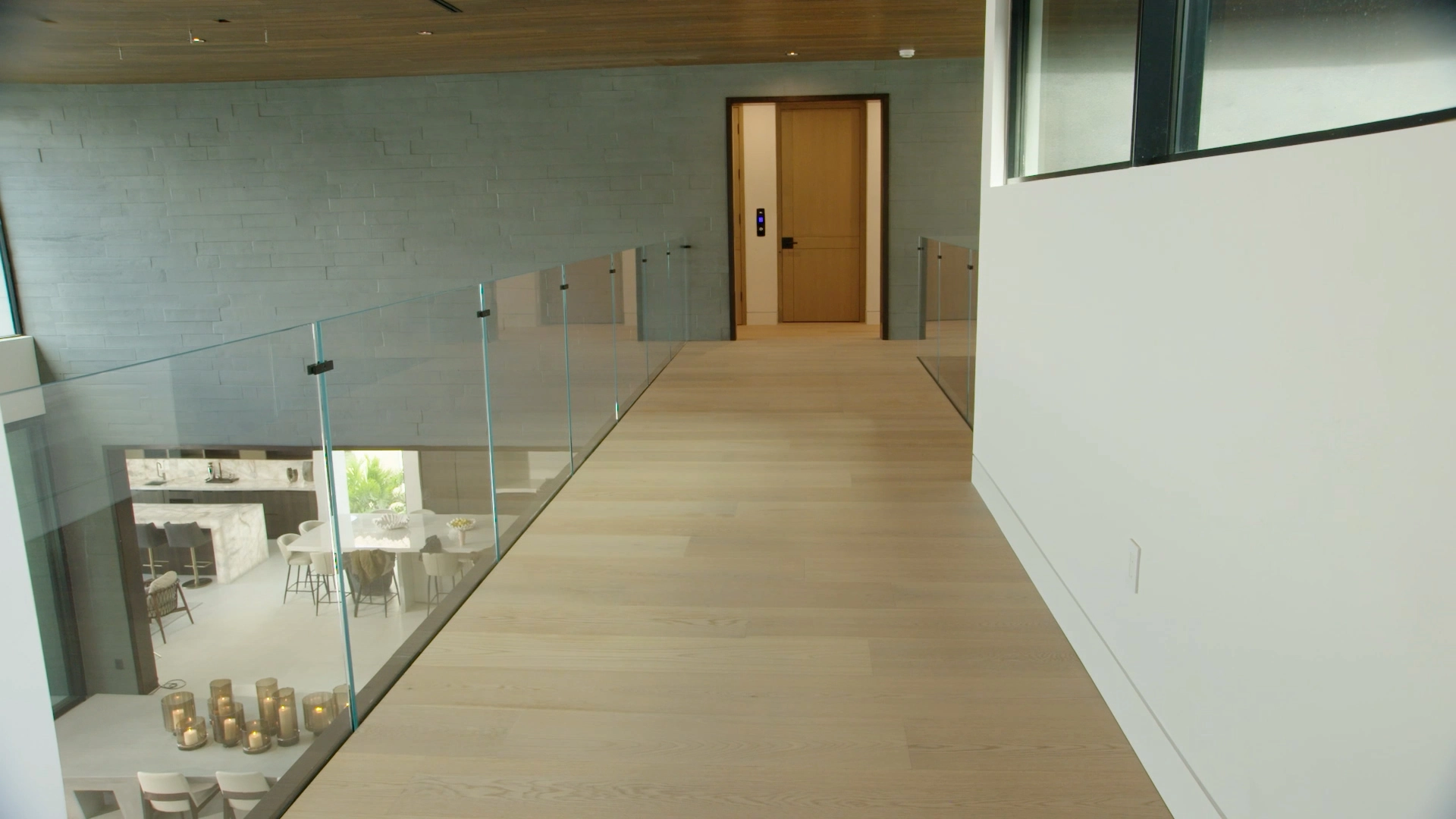 Glass railing runs the length of an upper hall open to the room below