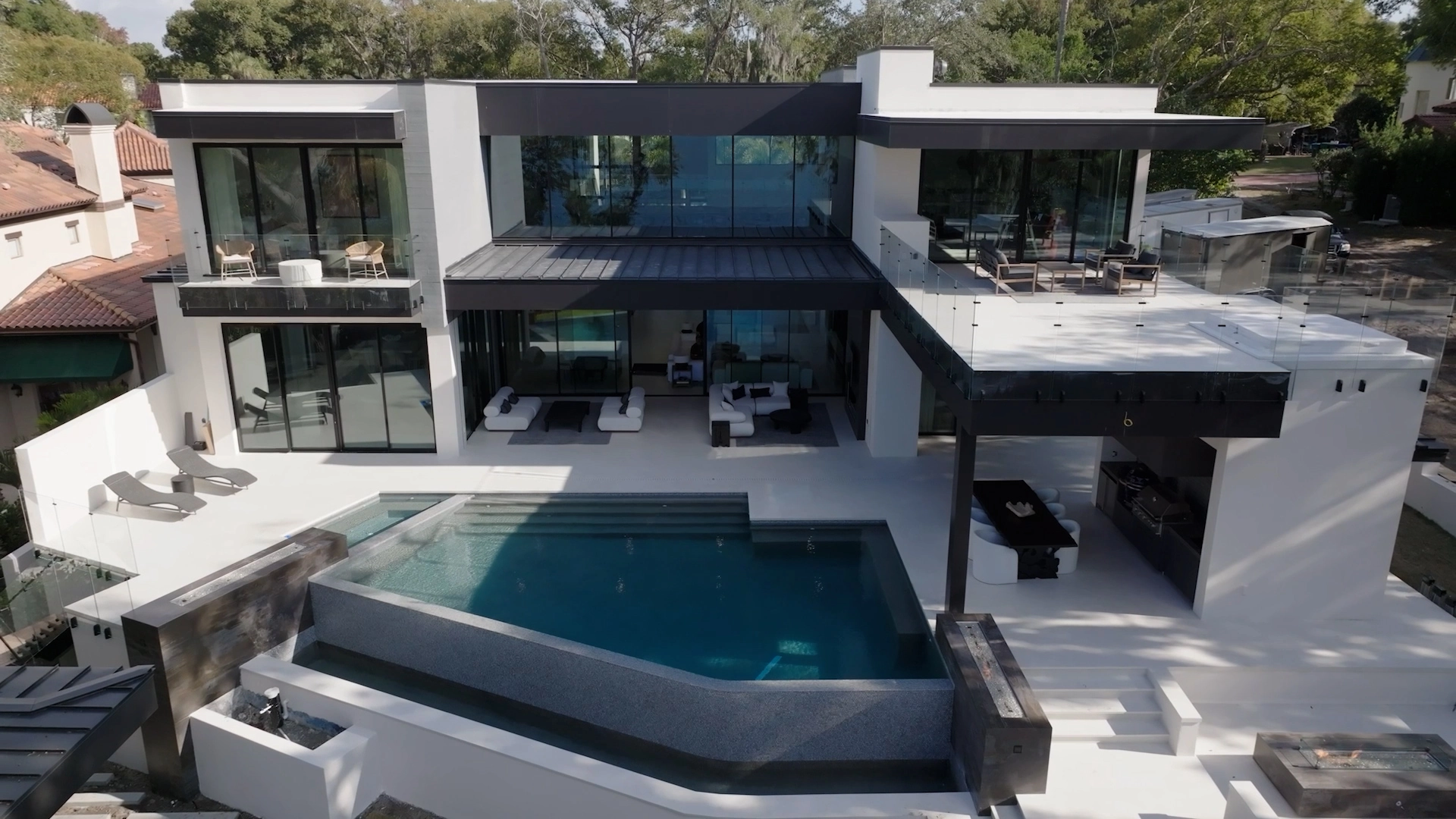 A white two-story home wraps a pool and deck in an overhead view