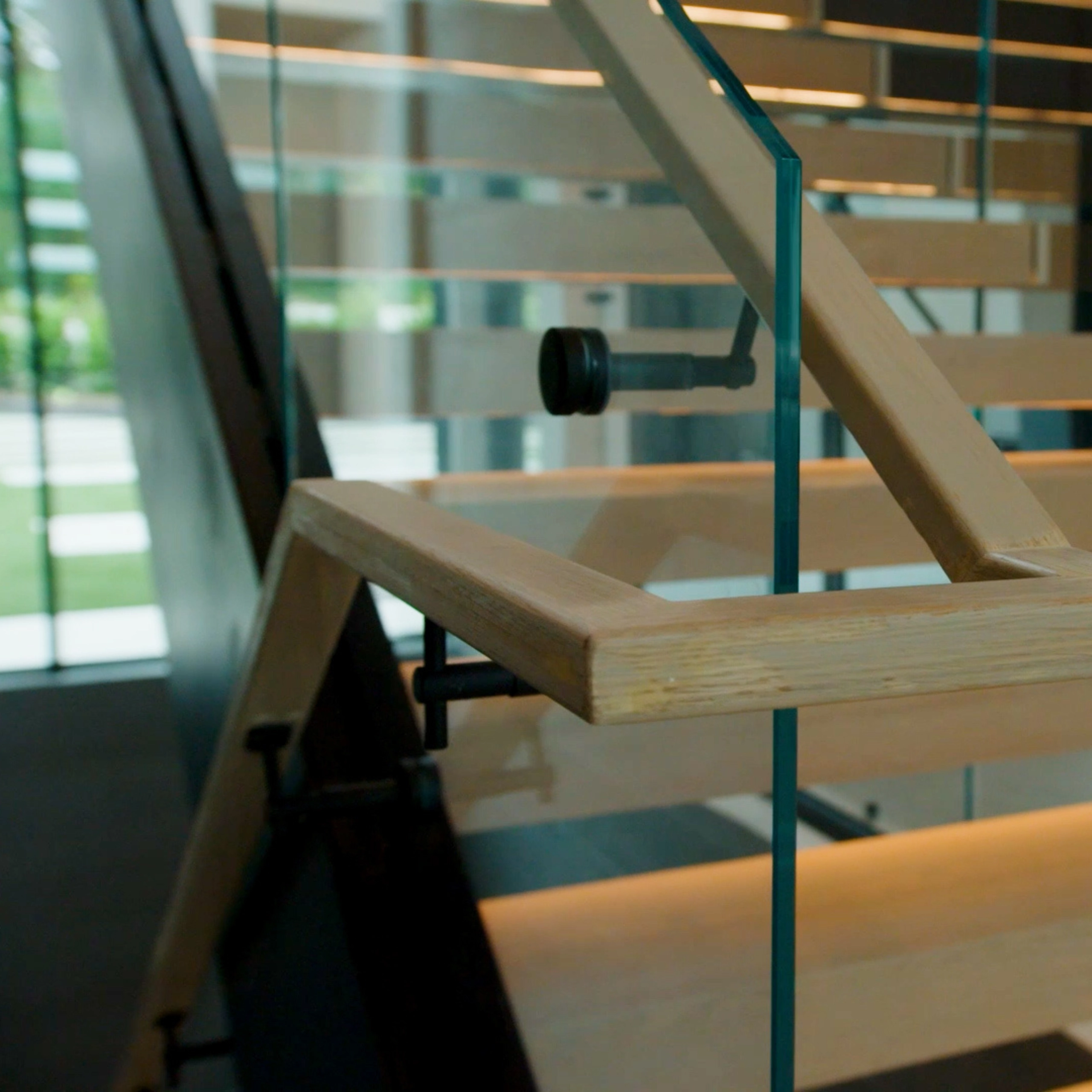 Close-up of a wood handrail mitered at a turn on a slim black bracket