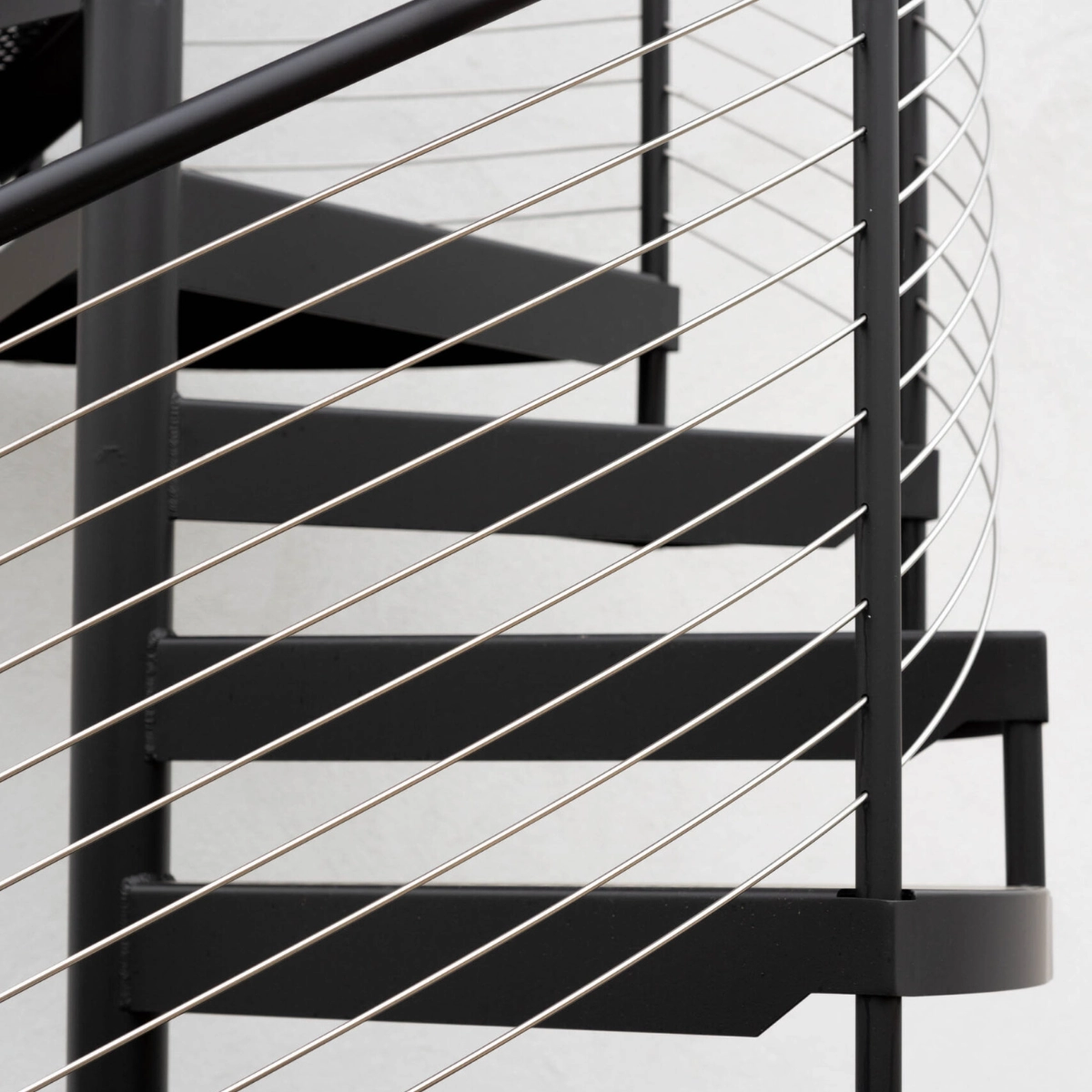 Cable lines pass across the edges of a black spiral stair's treads