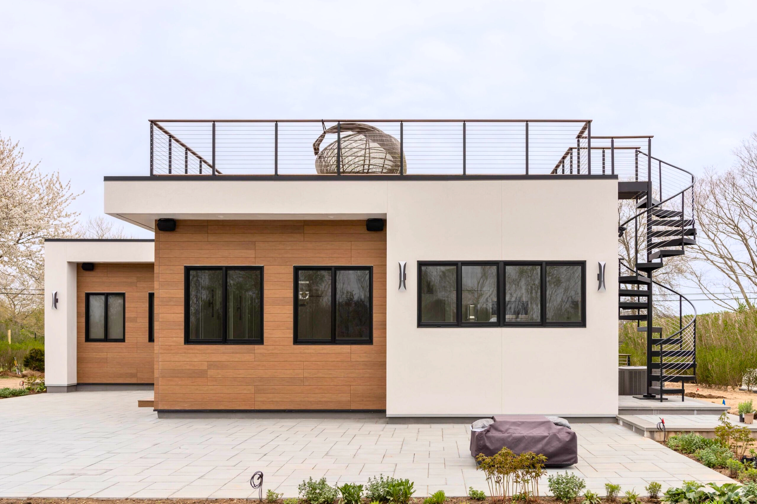 A spiral stair connects the yard to a roof deck ringed in cable railing