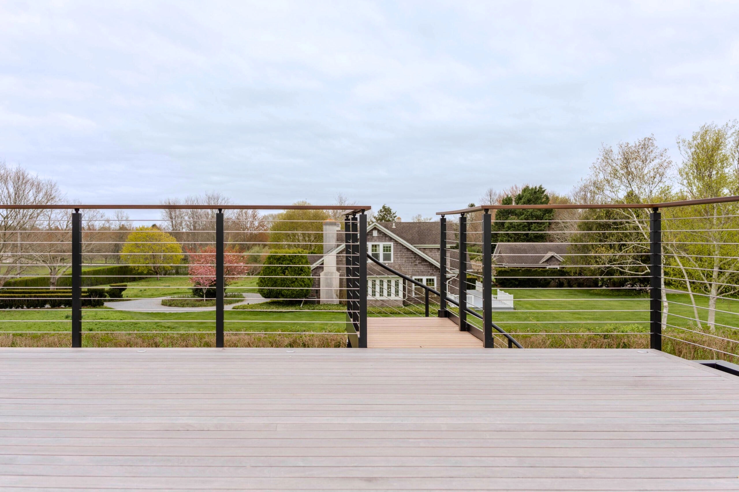 Cable railing frames a view across the lawn from an open deck