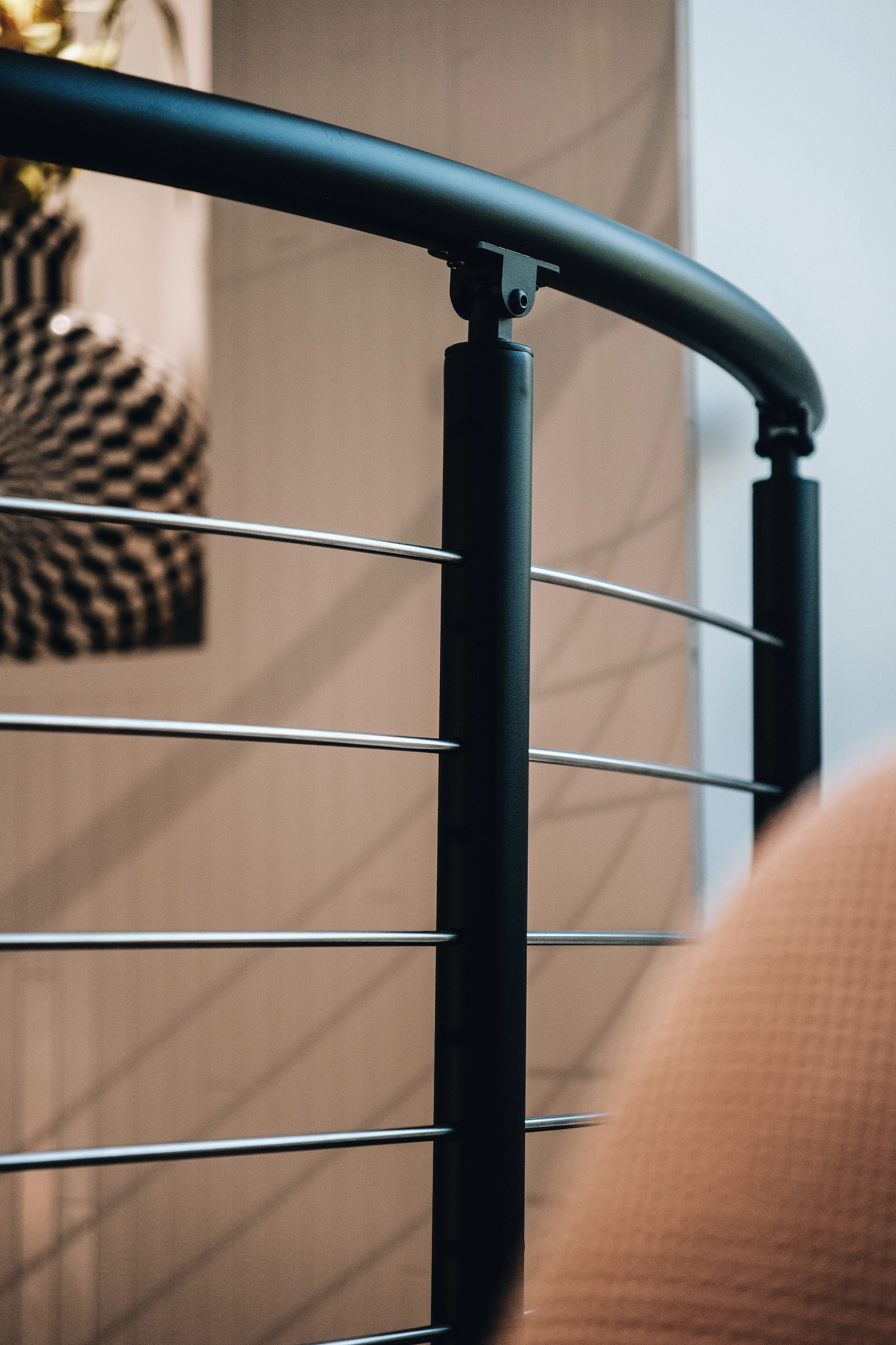Close-up of a curved black handrail above evenly spaced horizontal rods