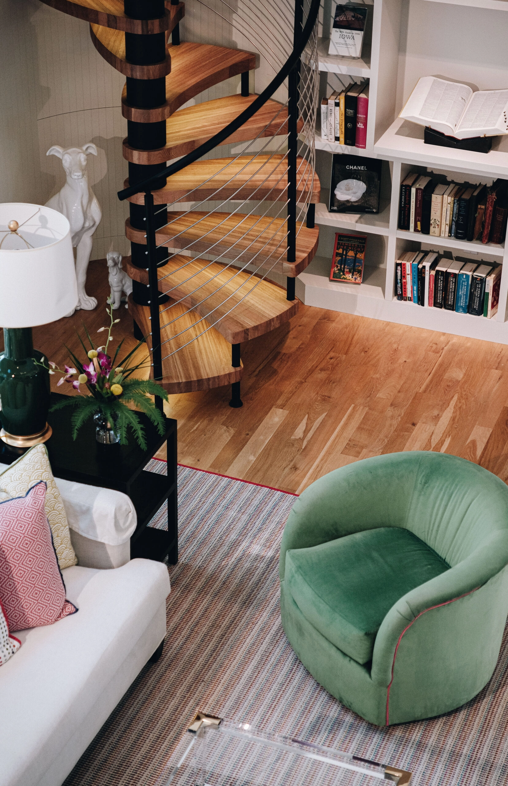 A spiral stair winds past built-in bookshelves in a library sitting room