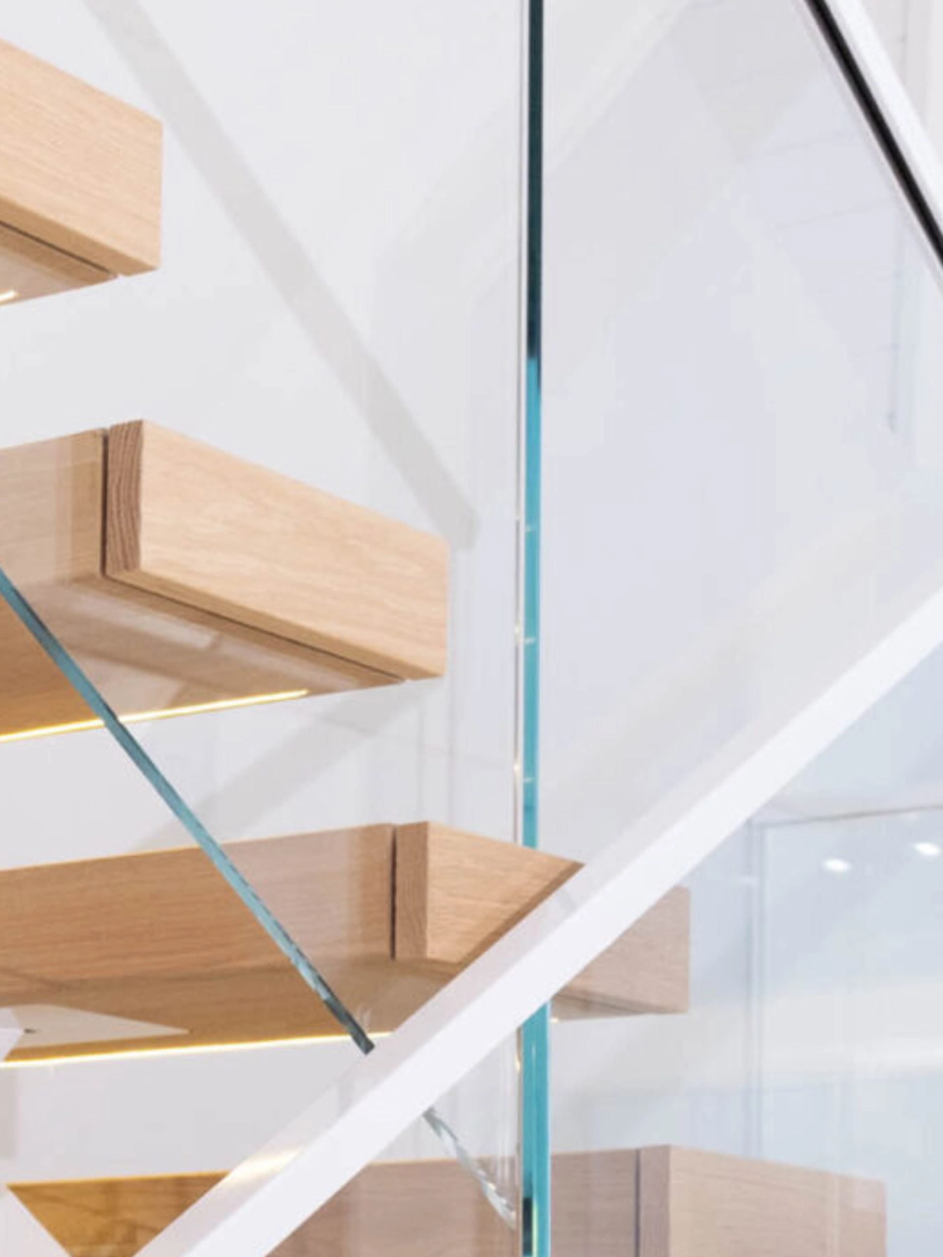 The glass panel passes straight through the treads of a floating stair