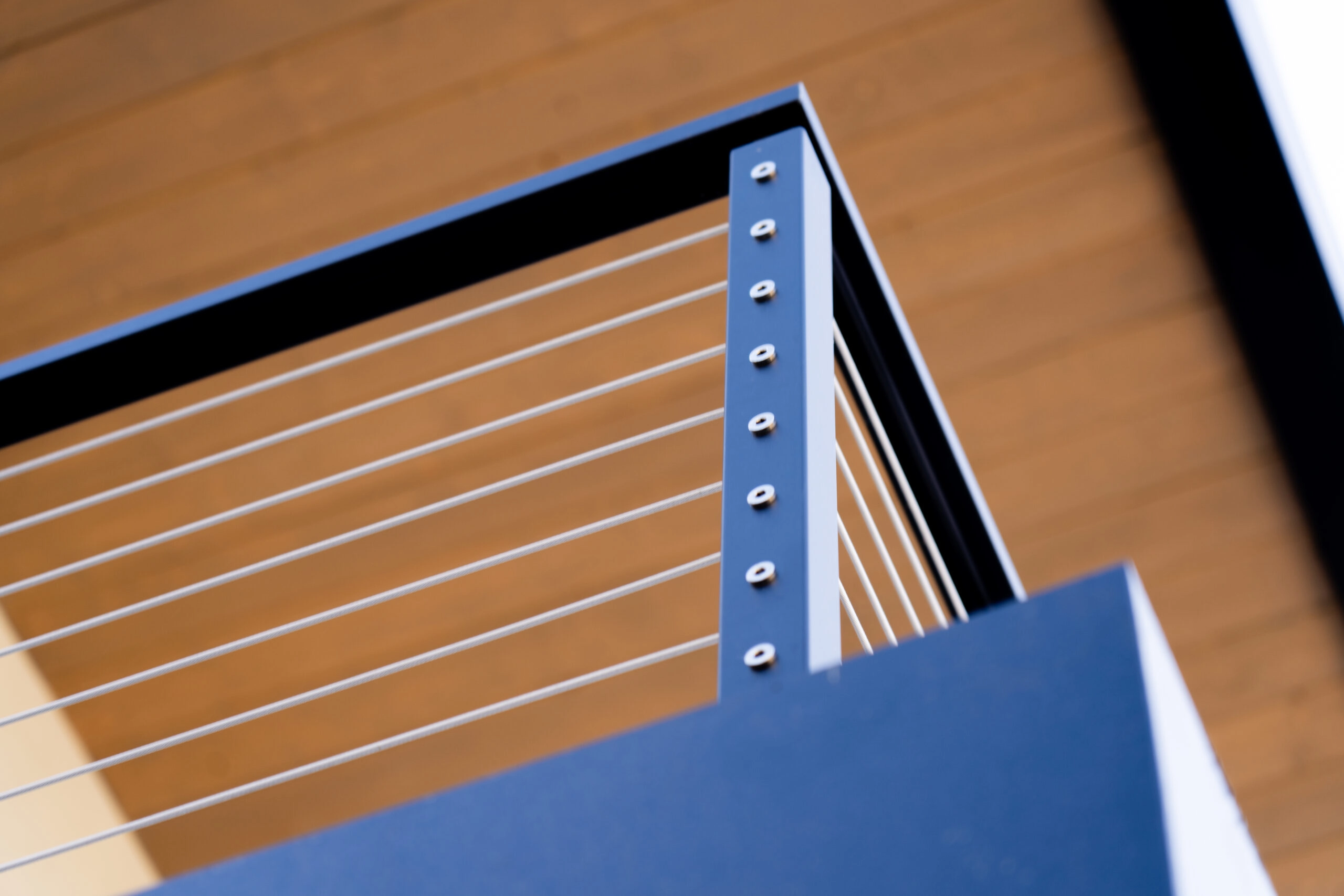 Close-up of a cable railing corner capped in wood against an open sky