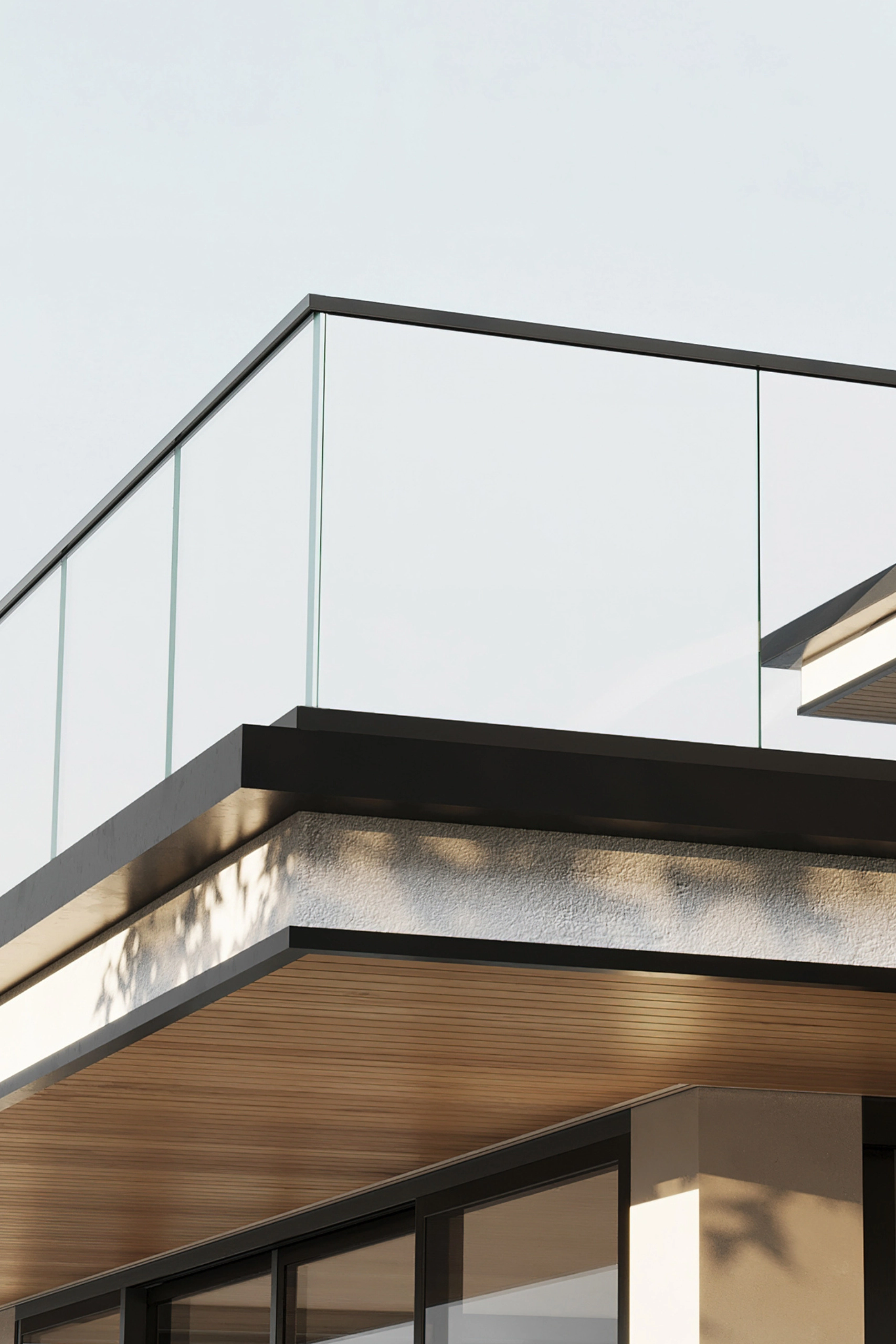 Close-up of a black base rail and top rail holding glass at a balcony corner