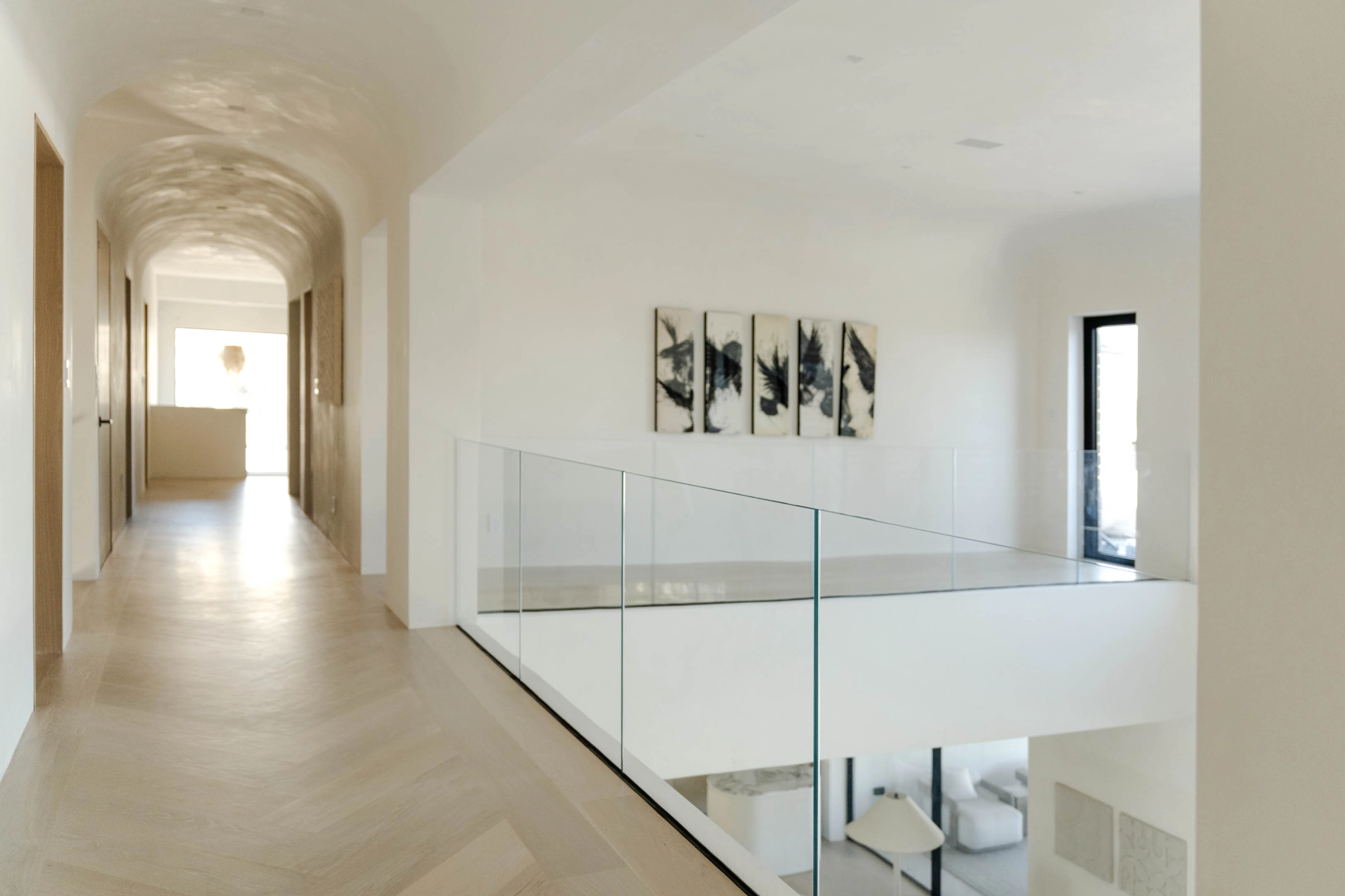 A vaulted hallway runs beside a glass railing with its mounts tucked away