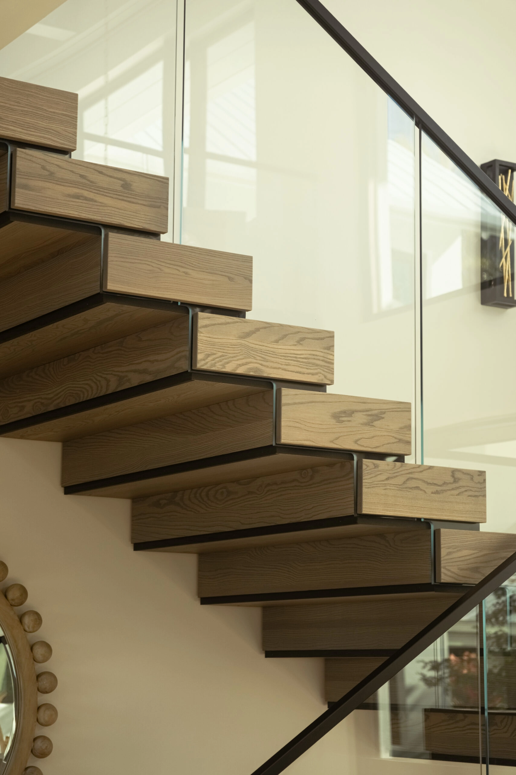 Box treads step past a glass panel held tight to the stair edge