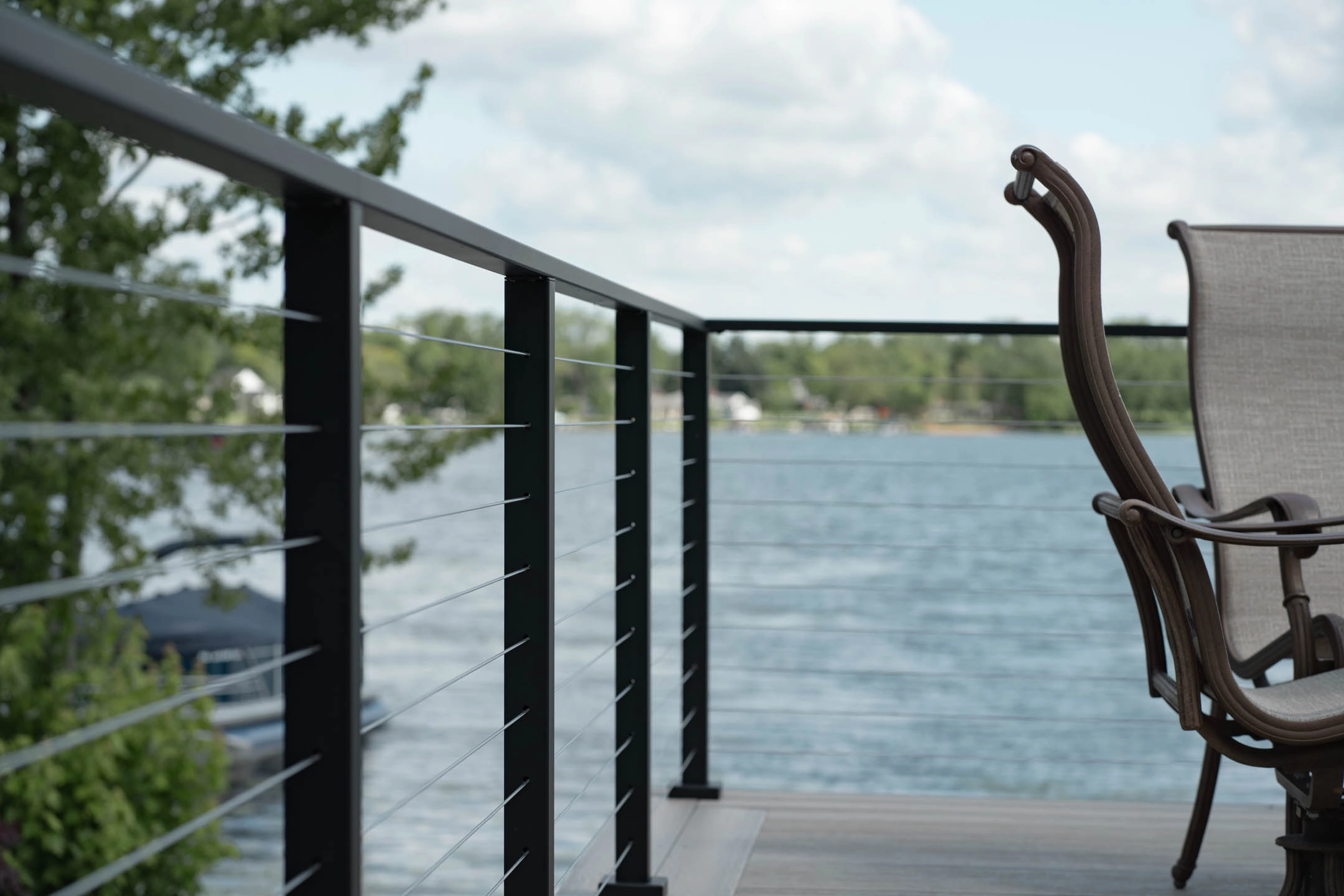 Cable railing turns a corner on one post at a lakeside deck rail