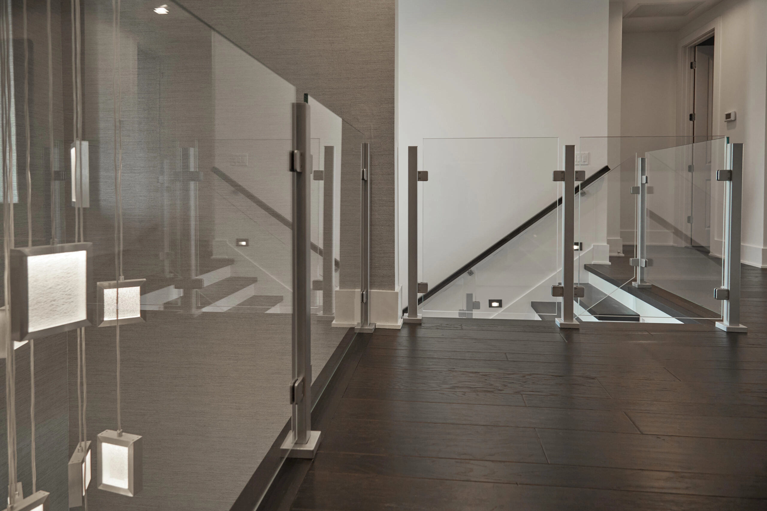 Glass panels clamp into metal posts along an interior balcony run