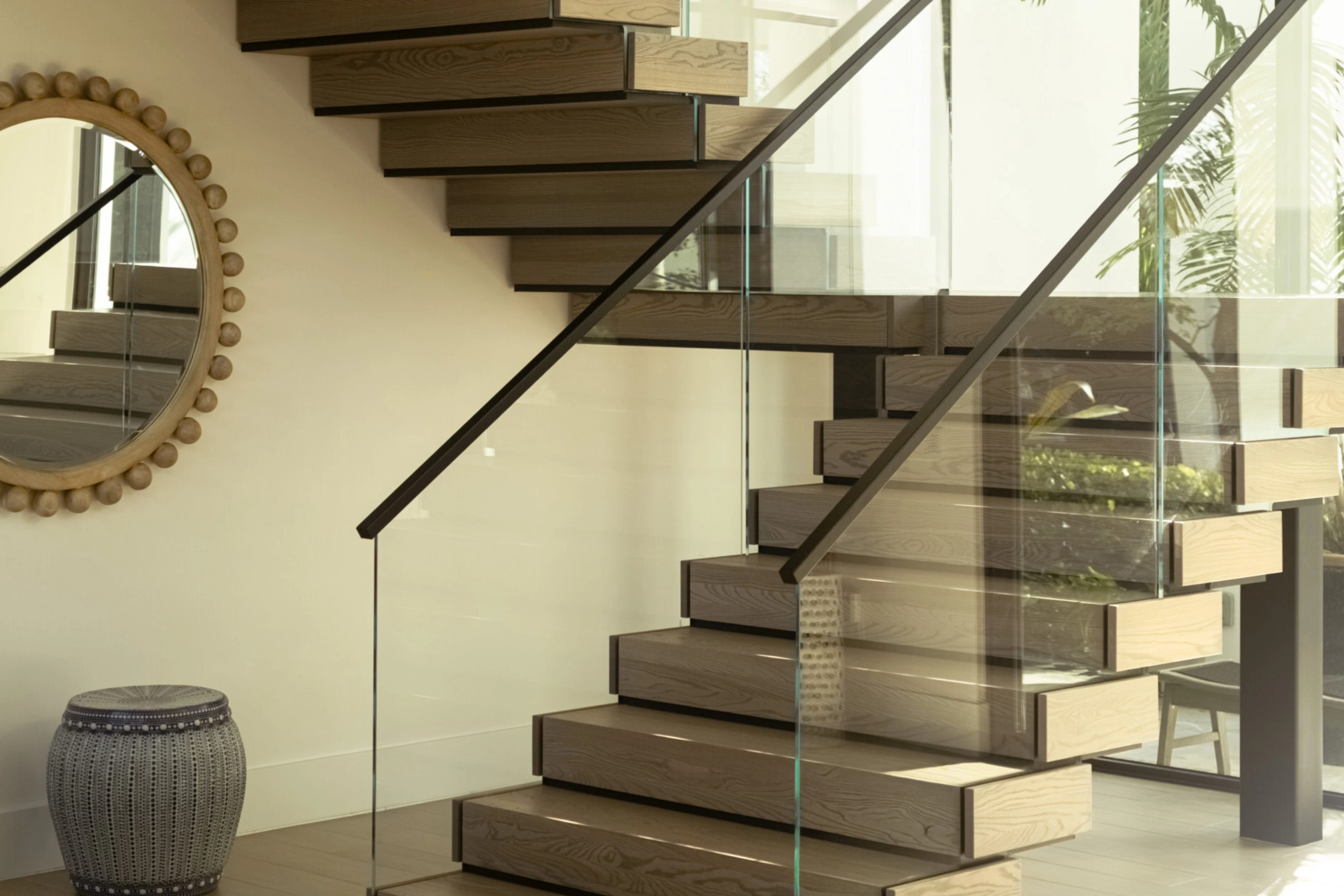 Box treads step past a round mirror behind a frameless glass panel