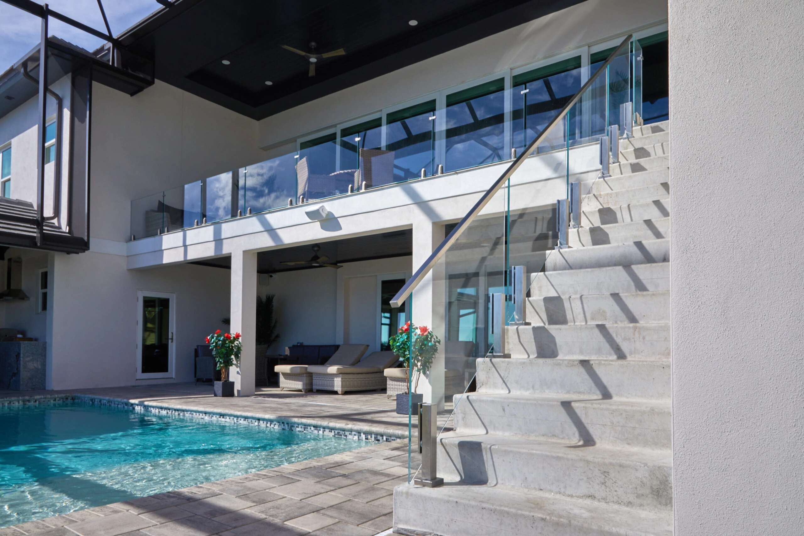 Glass railing lines an upper level above a pool and outdoor stair