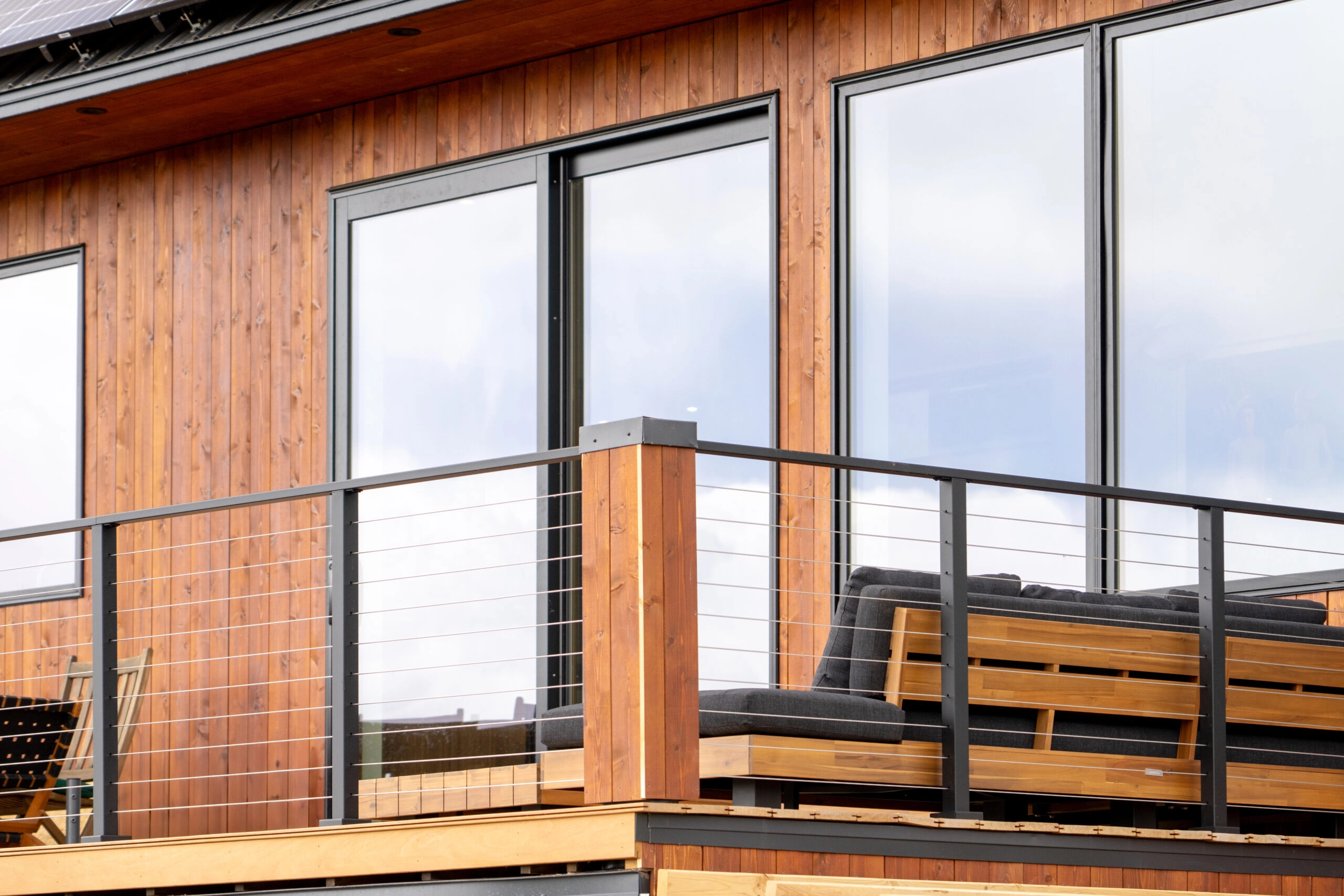 Cable railing runs along a wood-sided deck with a built-in bench