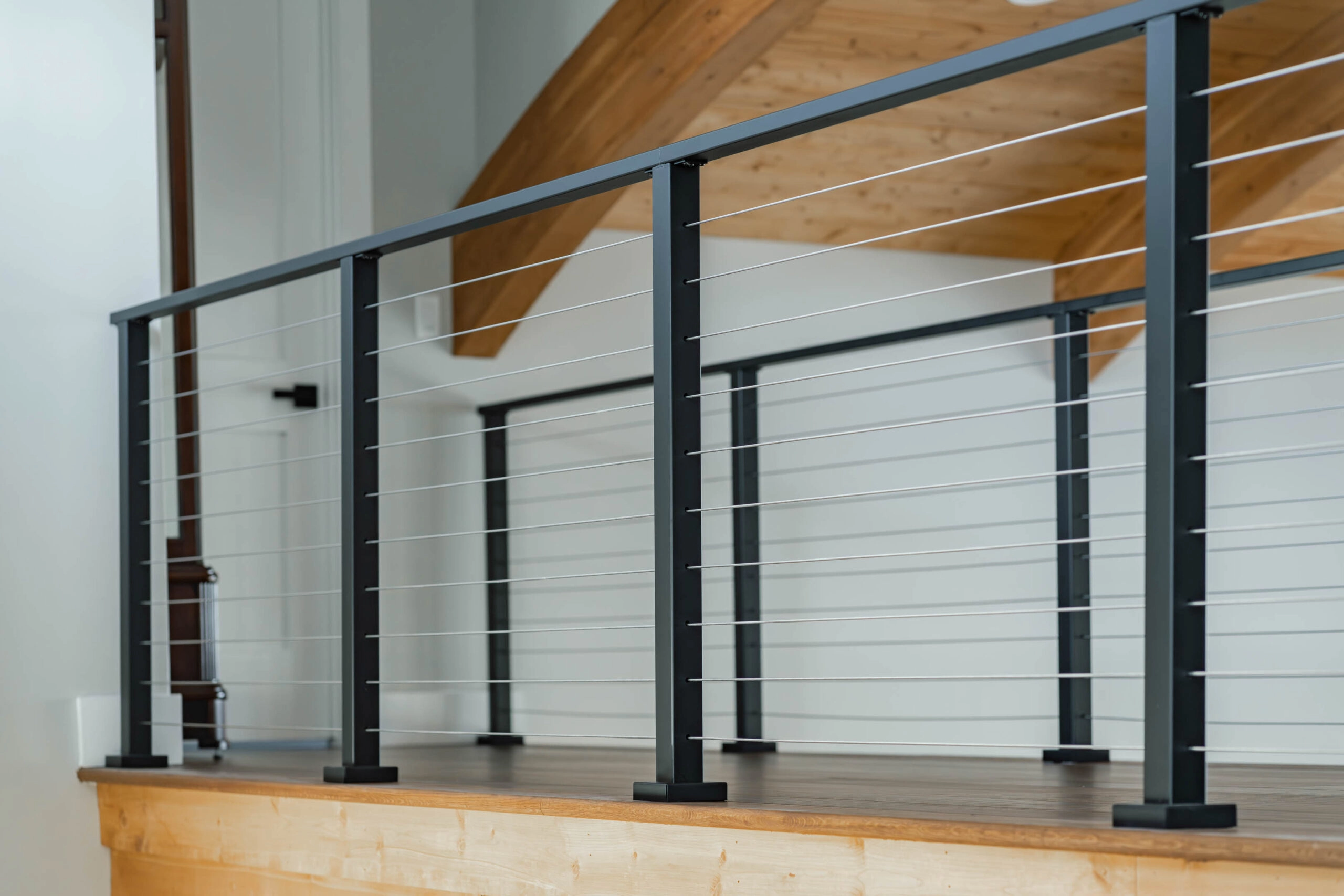 A level run of cable railing lines an interior catwalk under a vaulted ceiling