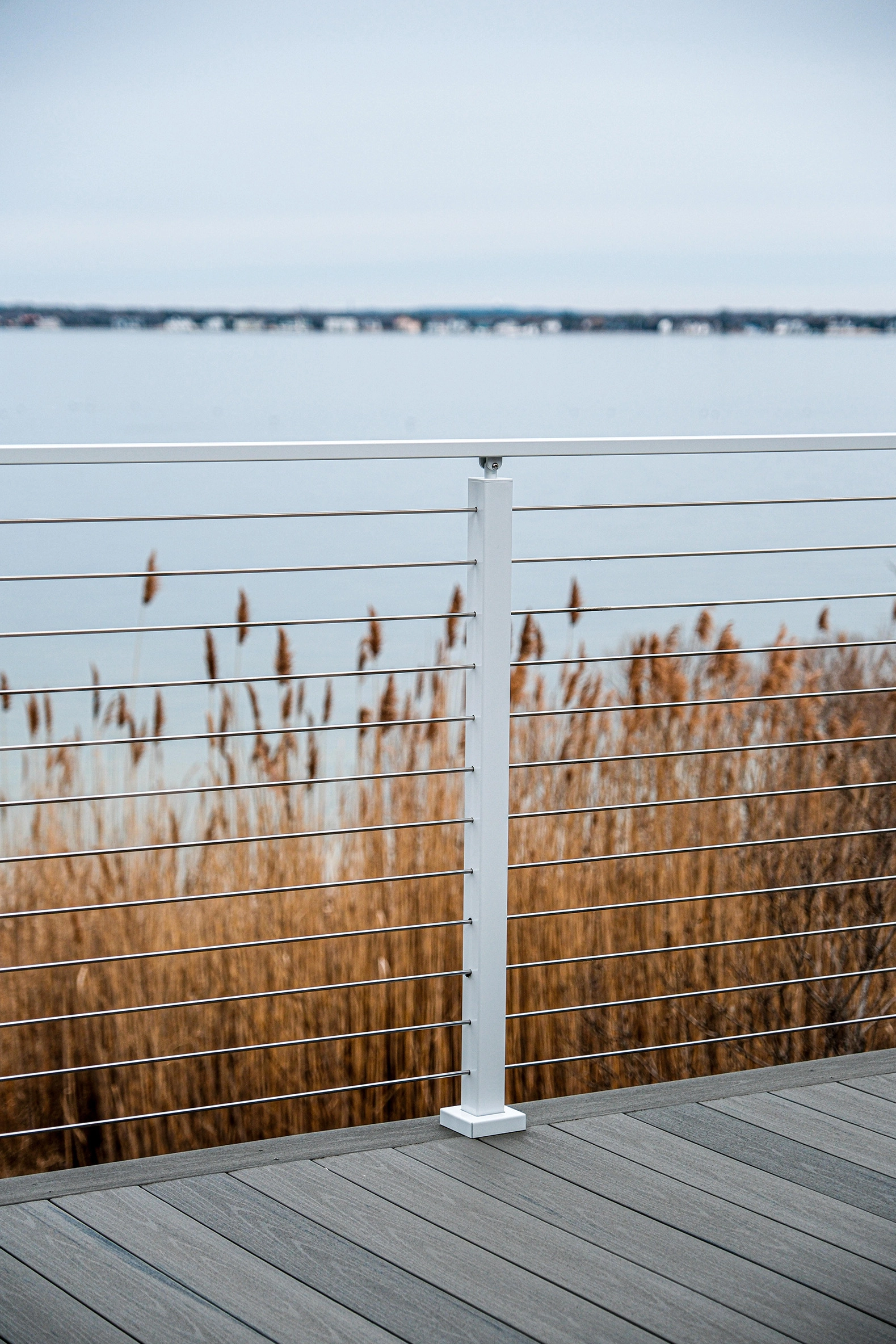 White posts carry rod infill along a boardwalk edged with beach grass