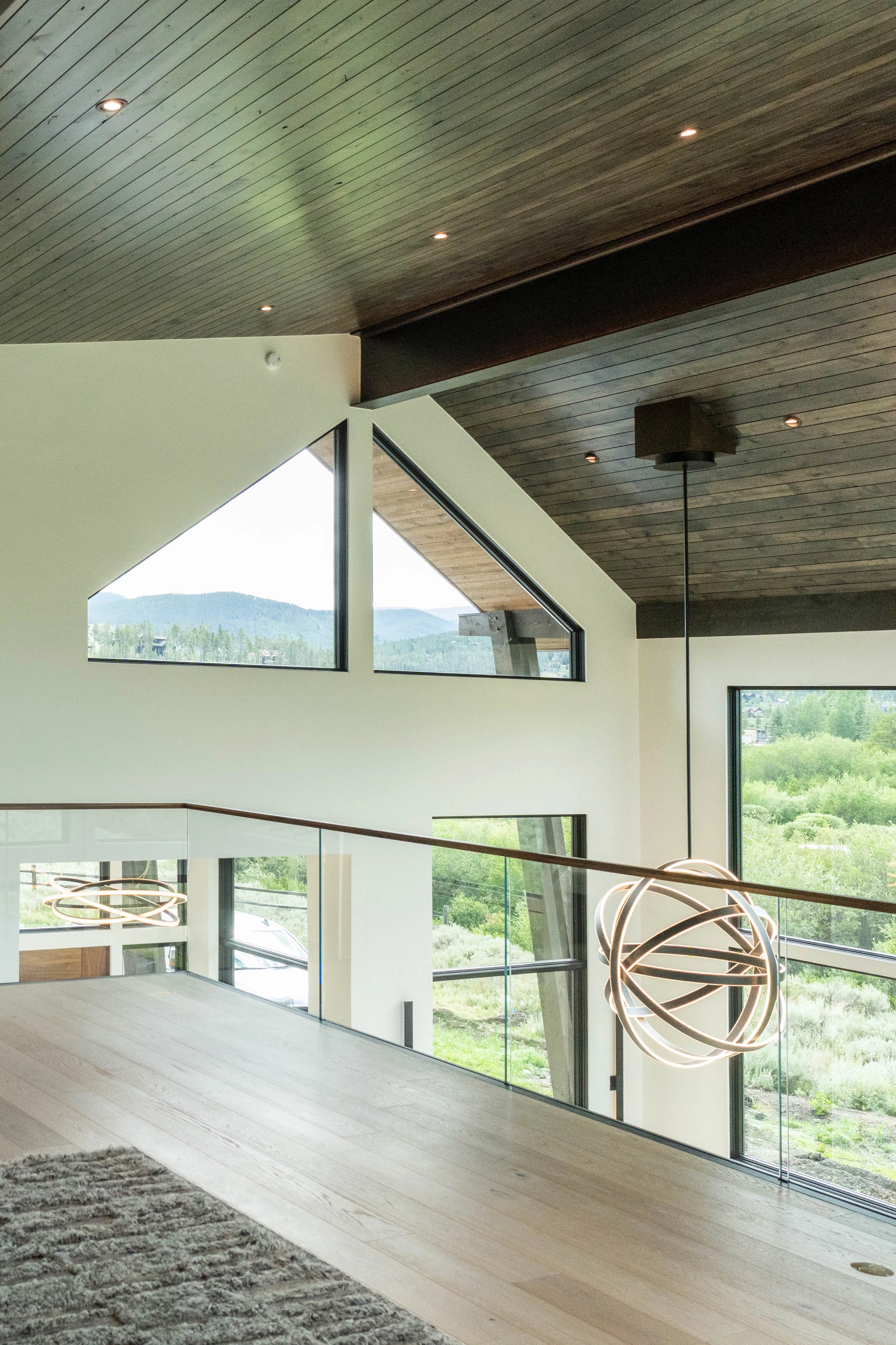 Glass railing set flush into the floor edges a loft under a wood plank ceiling