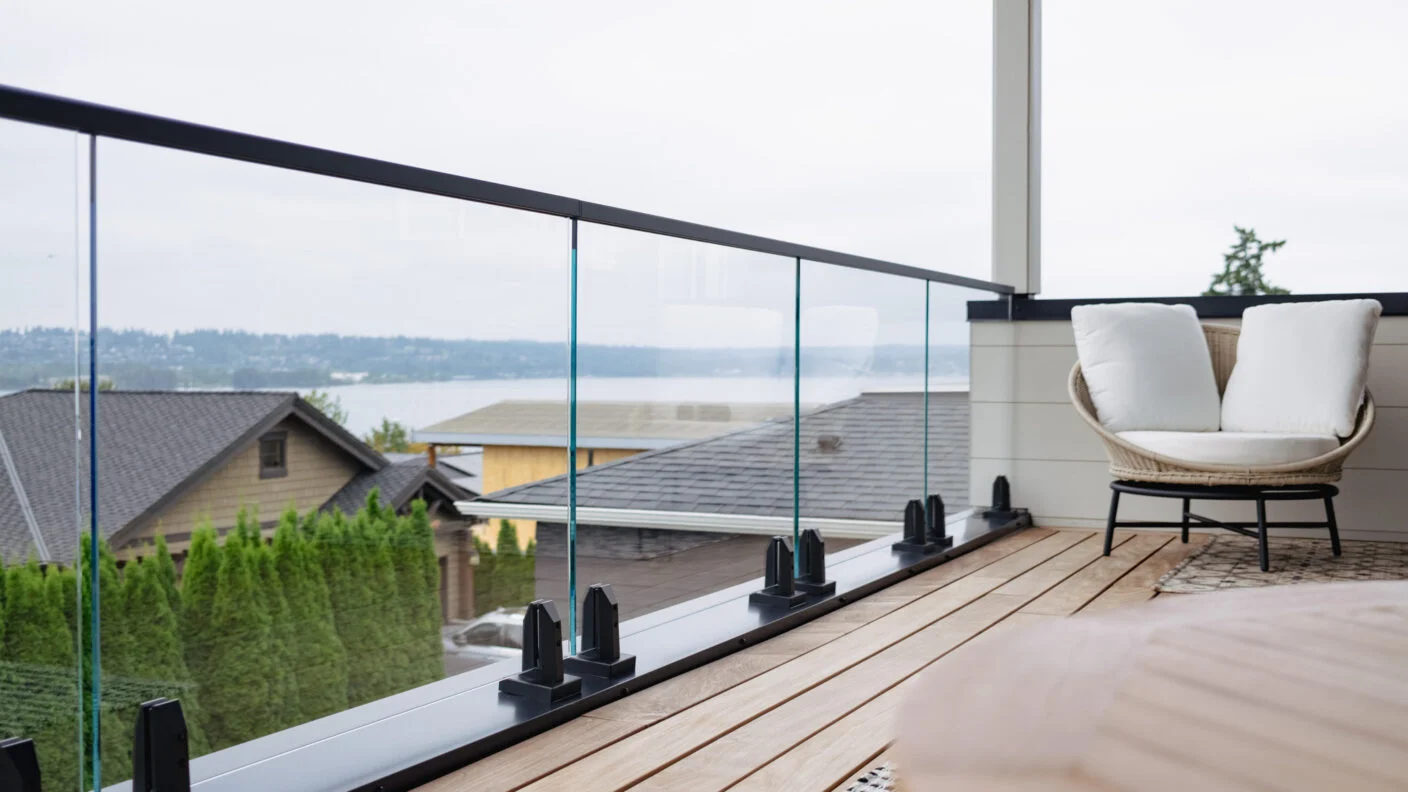 Spigot-mounted glass railing frames a lake view from a wood deck