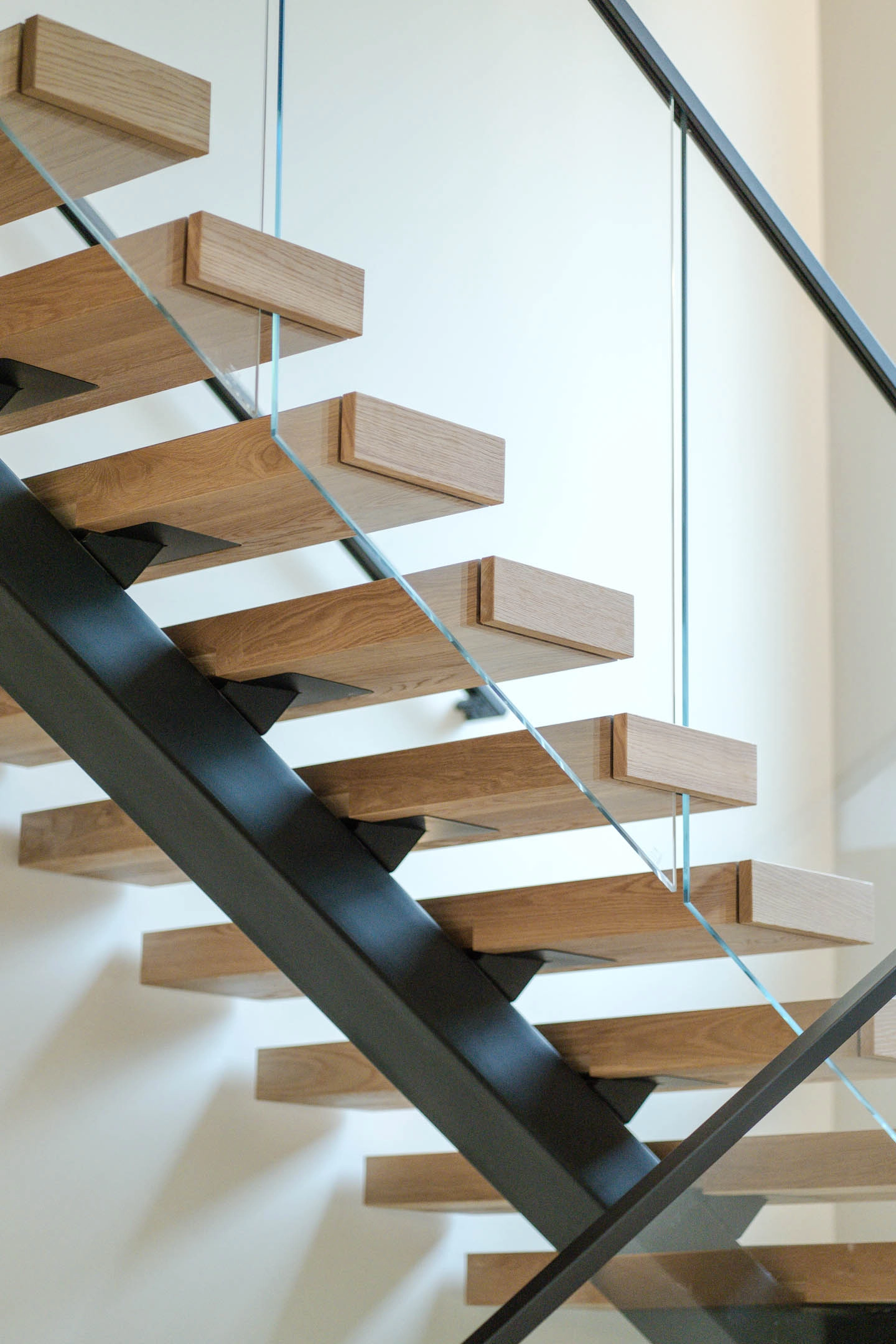 Treads cantilever from a black stringer with glass panels set into their edges