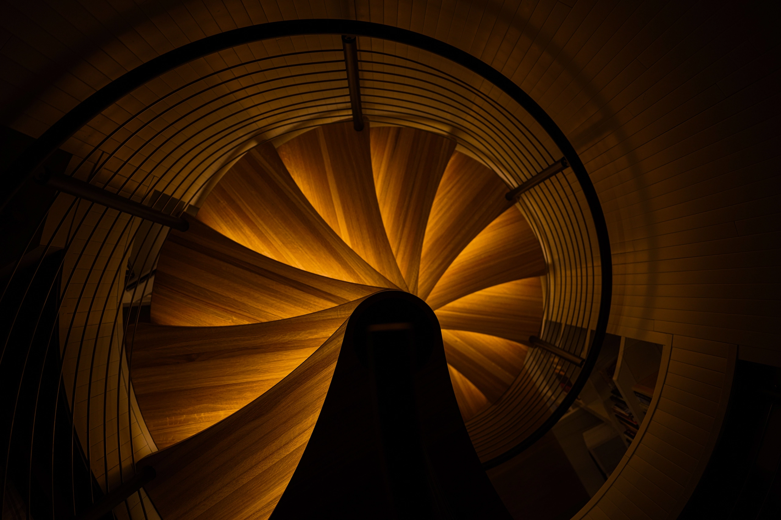 Looking down a spiral stair with every tread edge lit from beneath