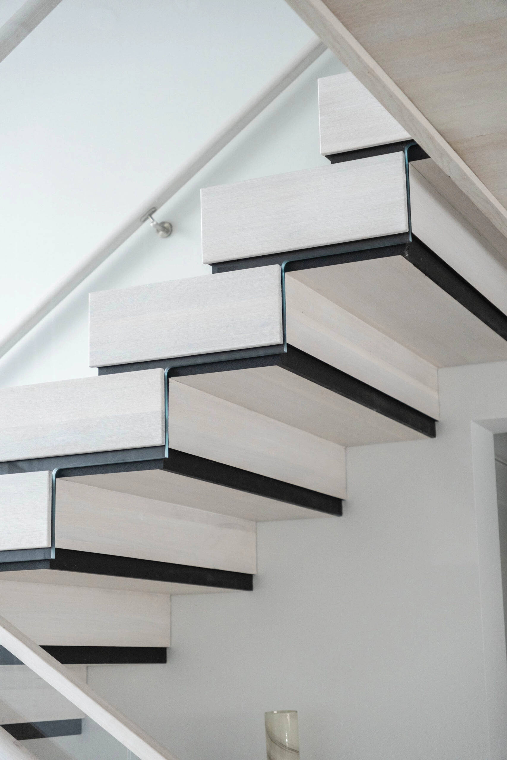 Close-up beneath stacked treads finished in white with black edges