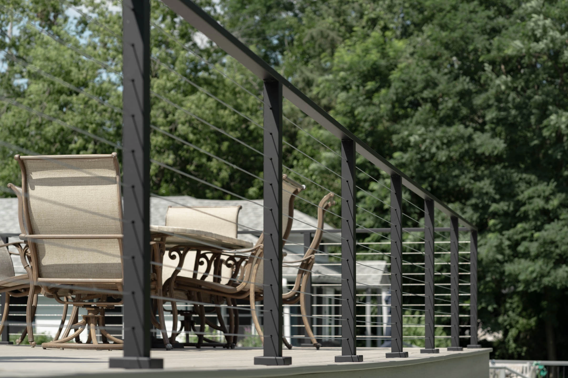 Cable railing rings a shaded deck set with an outdoor dining table