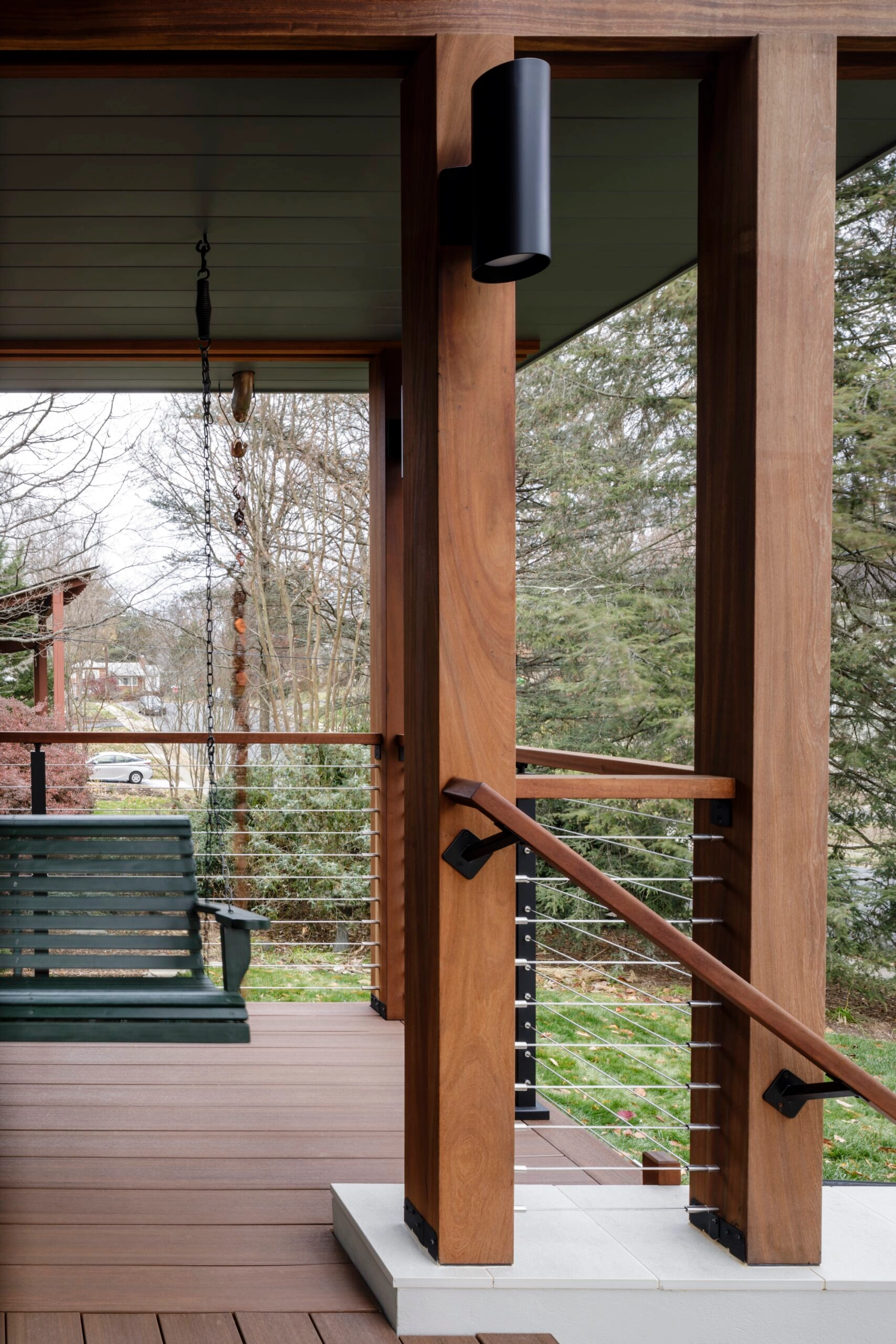 Cable railing frames a covered porch with a swing hanging in the distance
