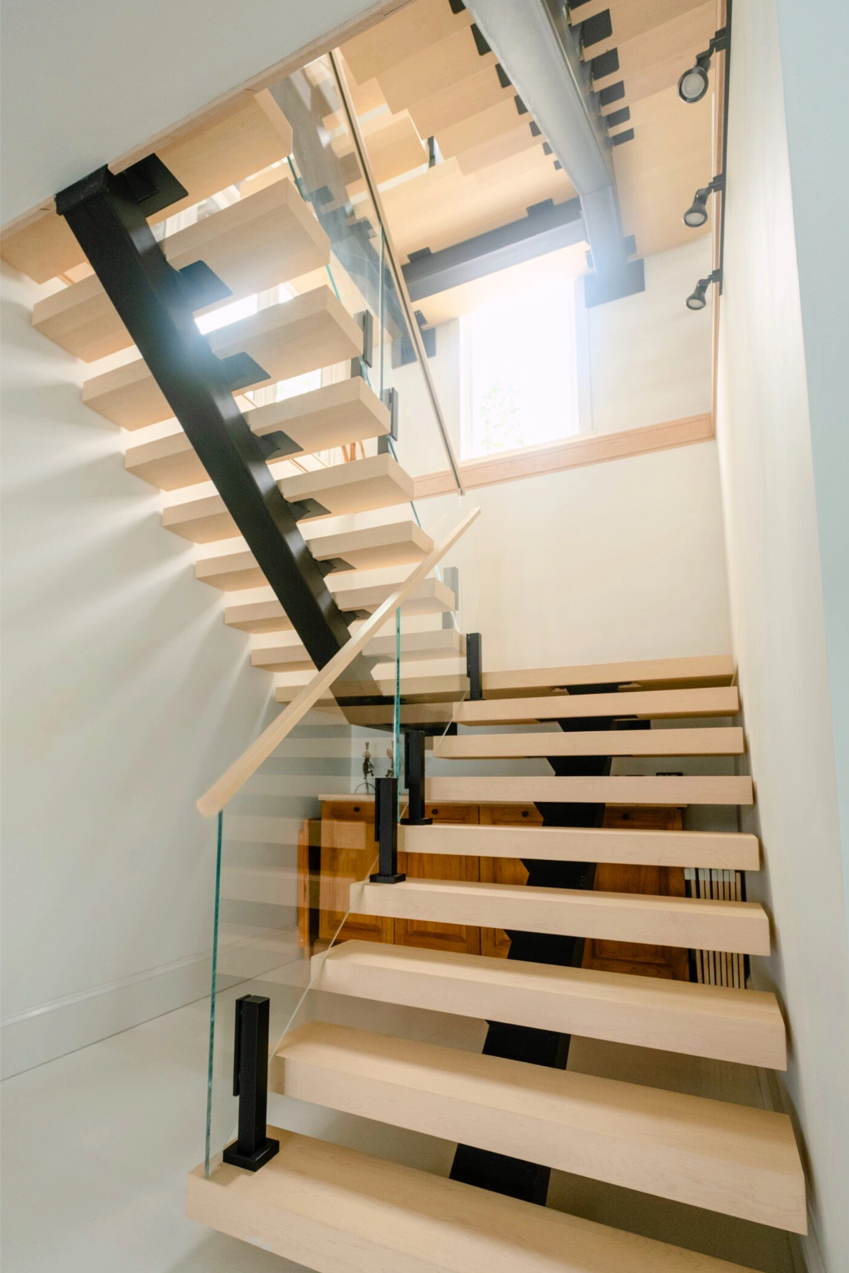 FLIGHT Mono stair with a single black center stringer and frameless glass railing