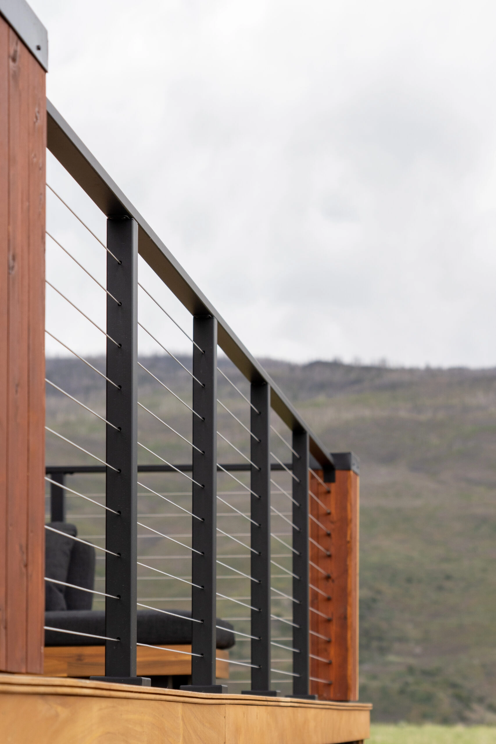 Cable railing steps down a porch stair beside a wood post and mountain view