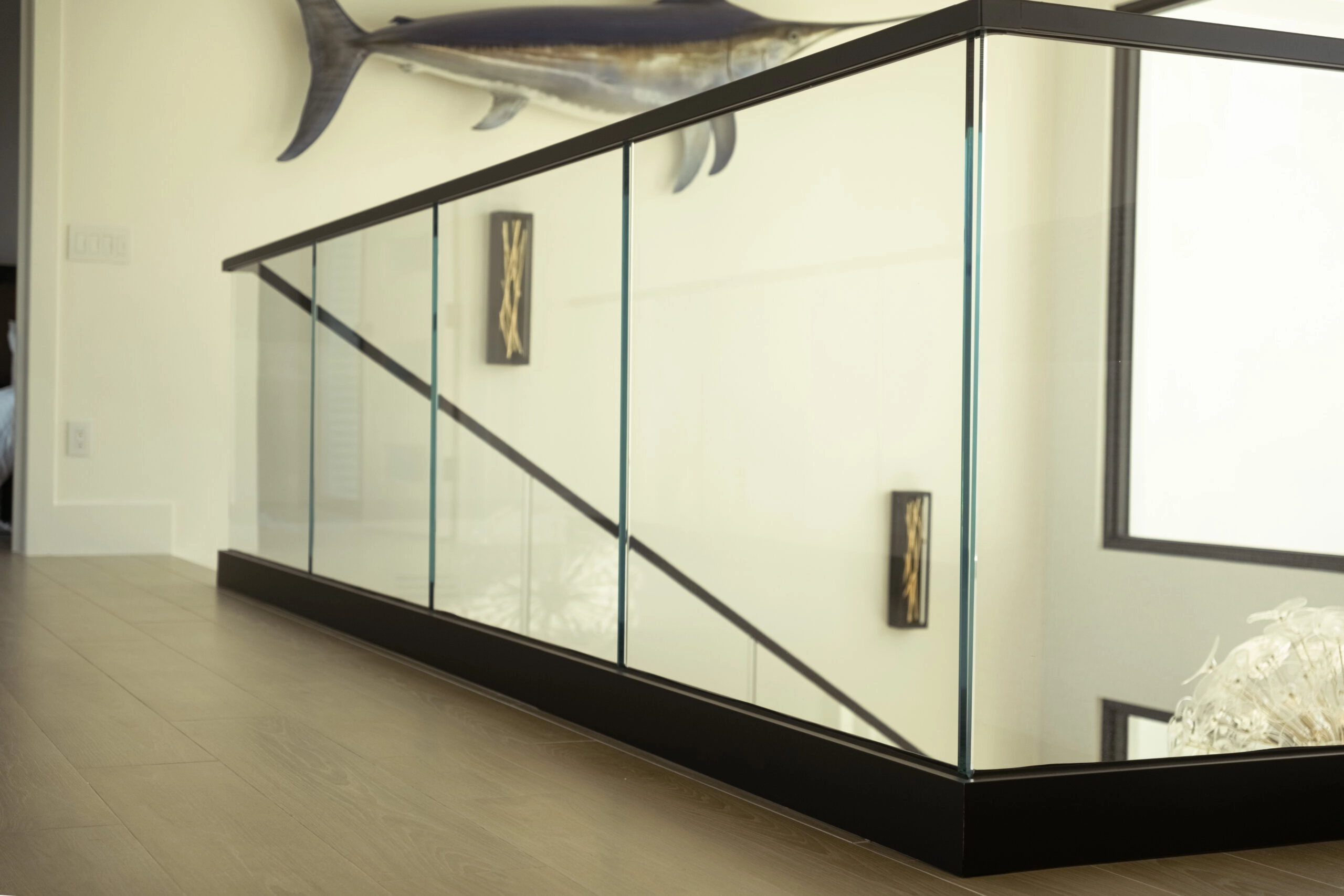 Black base rail carries glass panels around an upper landing opening