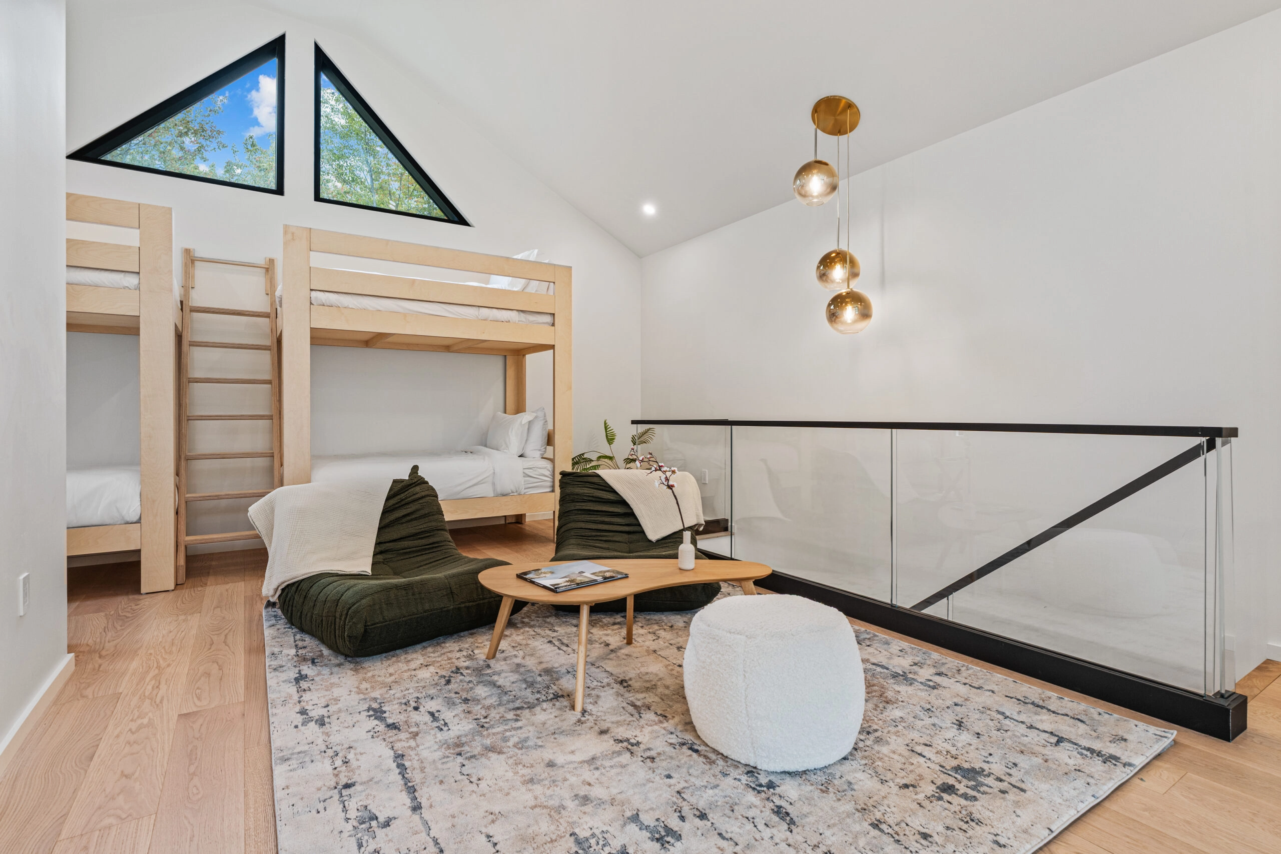 Glass railing in a black base rail guards a loft bunk room above the great room