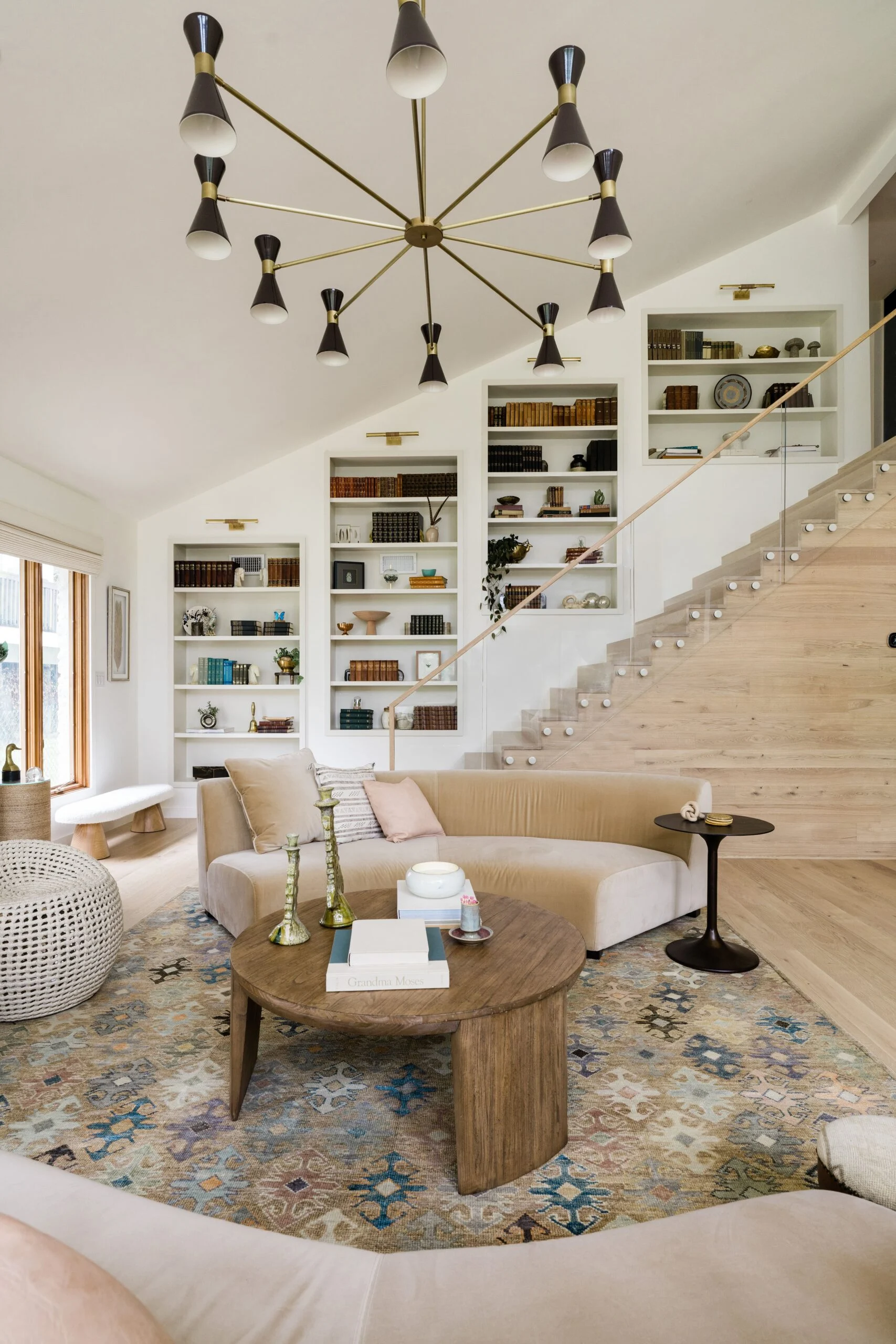 Glass railing borders a stair above a sitting room of white built-in shelves