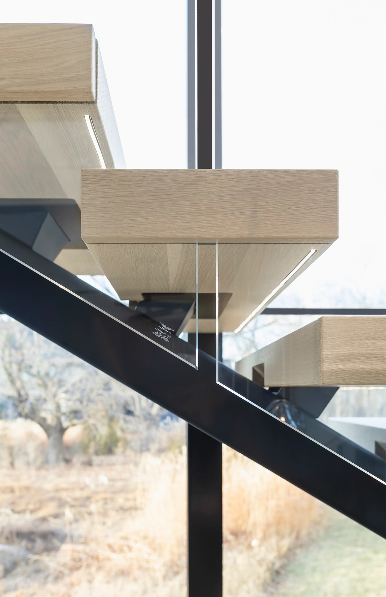 A glass panel slips through a tread edge beside a floor-to-ceiling window