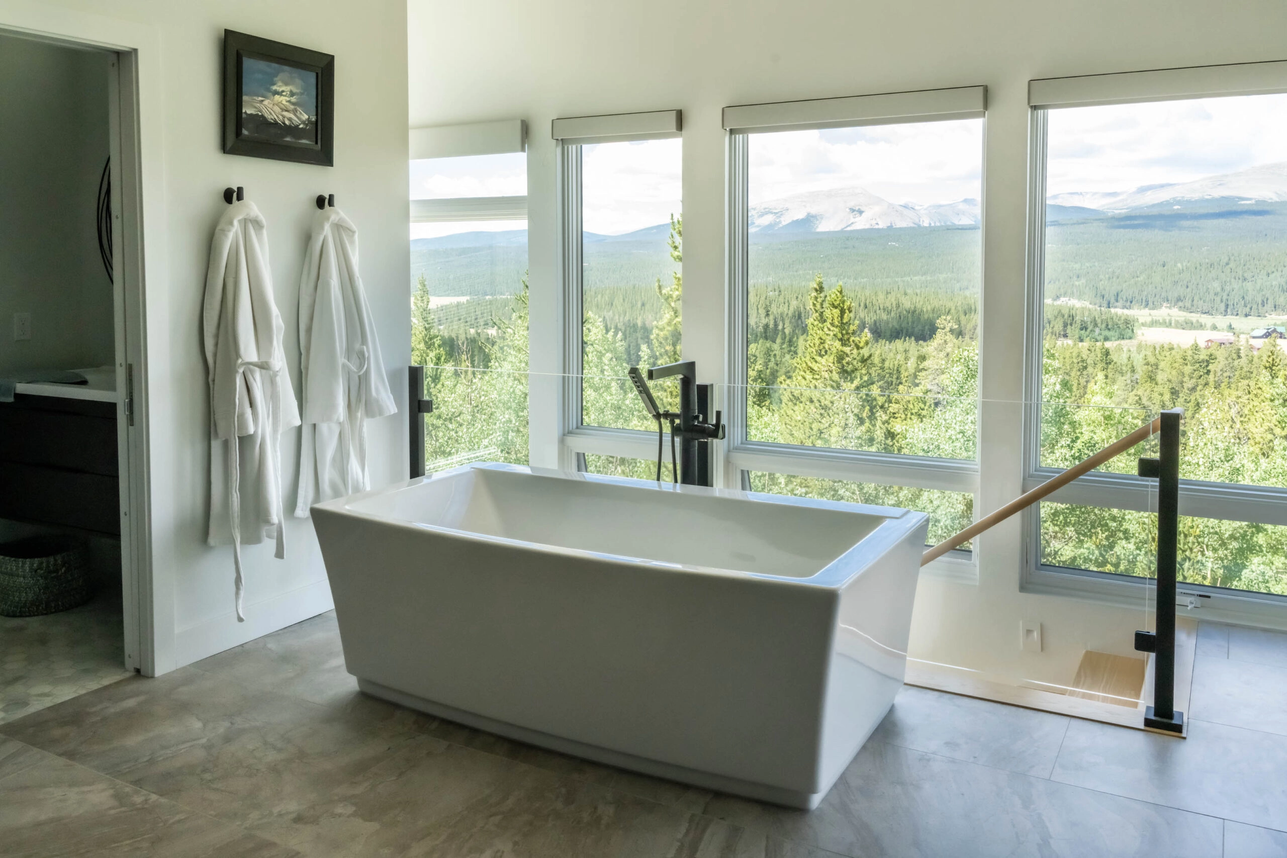 Black railing posts stand beside a freestanding tub facing a mountain view