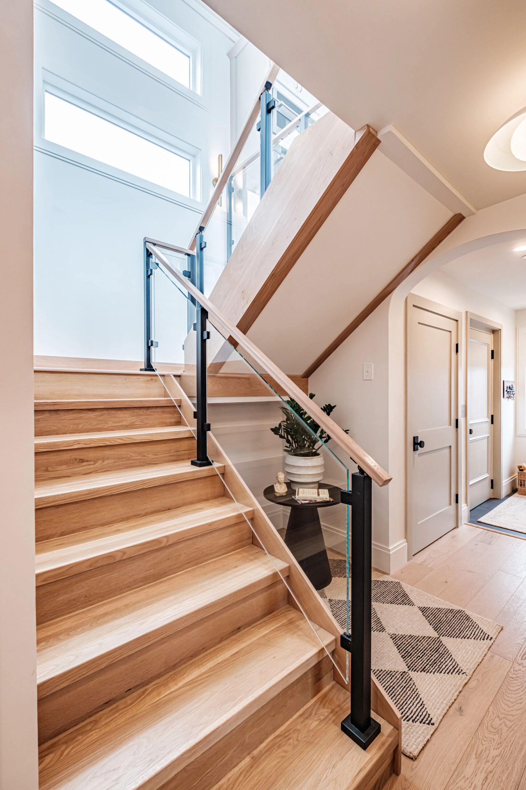 Glass panels between black posts follow a stair down to a lower hallway