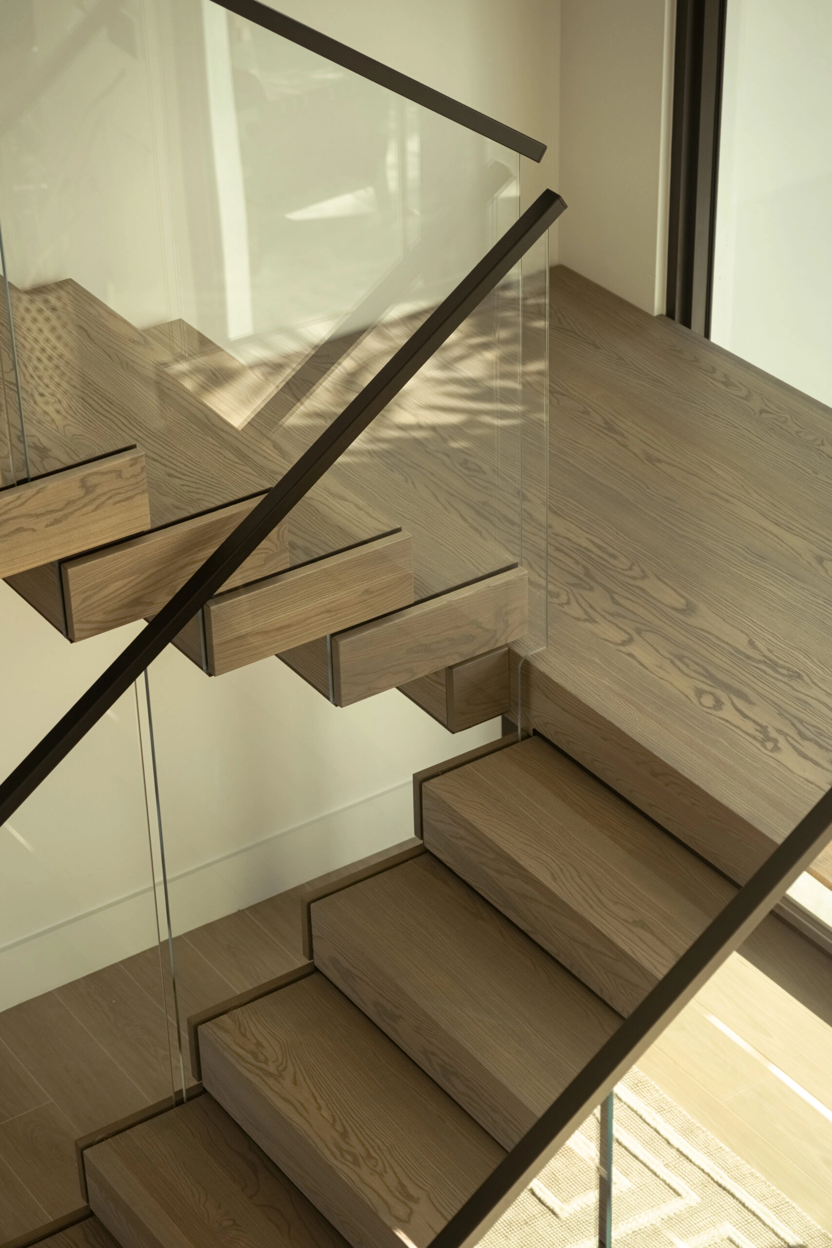 A switchback landing turns between glass panels seated in the stair itself